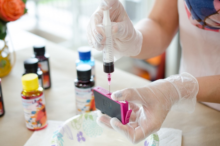 person filling an ink cartridge with ink