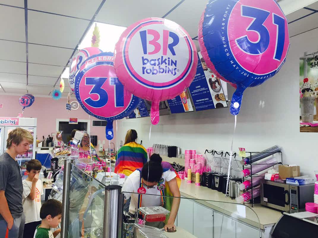 Baskin Robbins employees scooping ice cream with balloons that say 31 decorating the shop