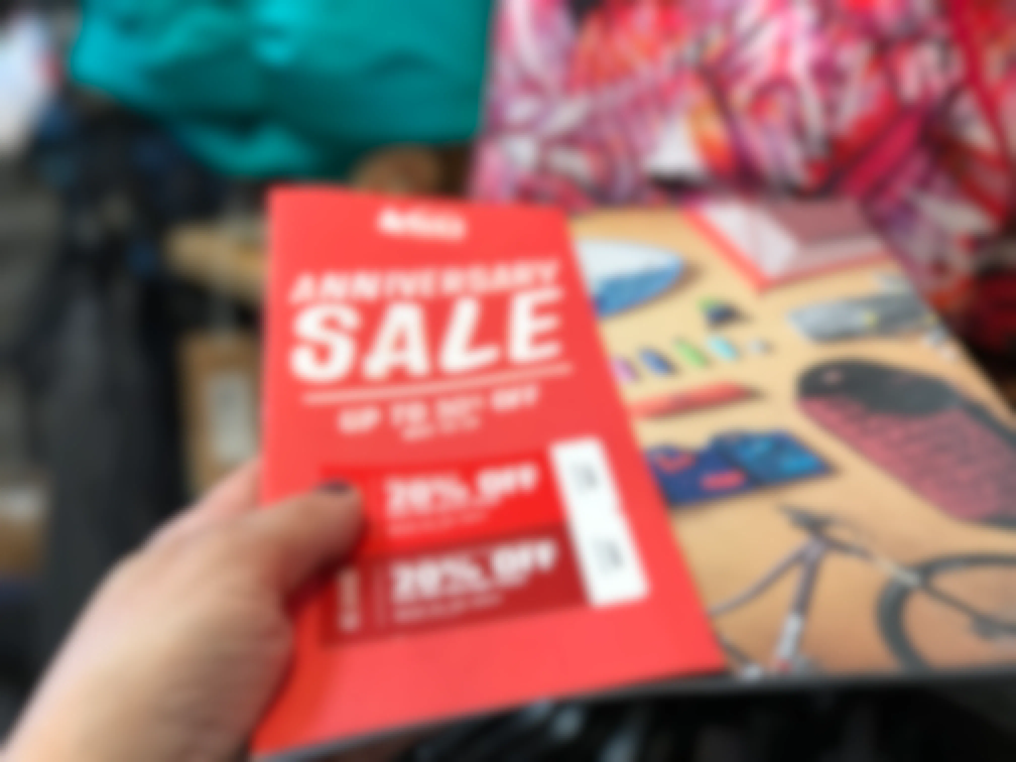 Person holing sale pamphlet from REI highlighting their anniversary sale