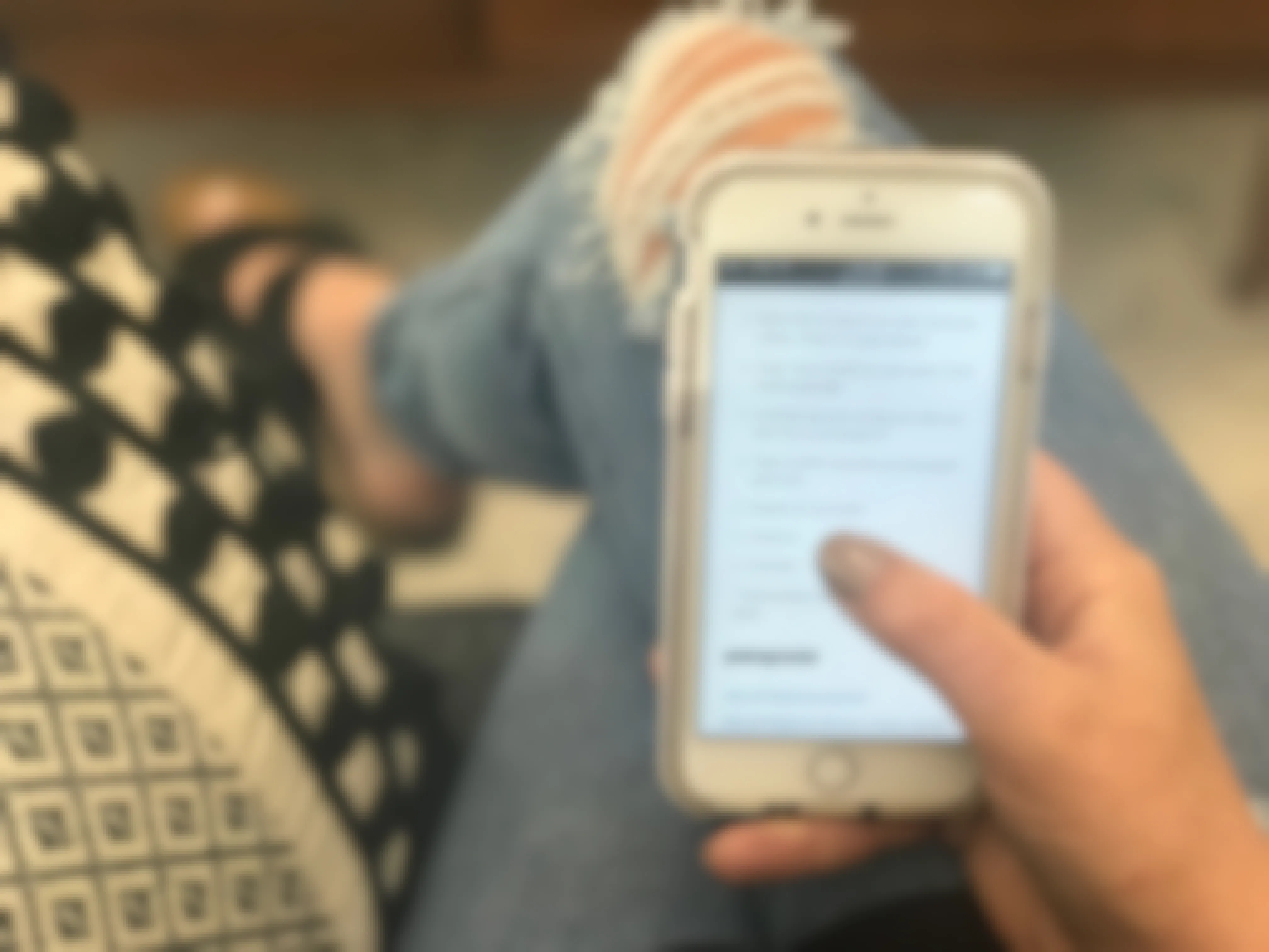 A person sitting on a couch with their phone displaying the REI website's information on REI sale lingo.