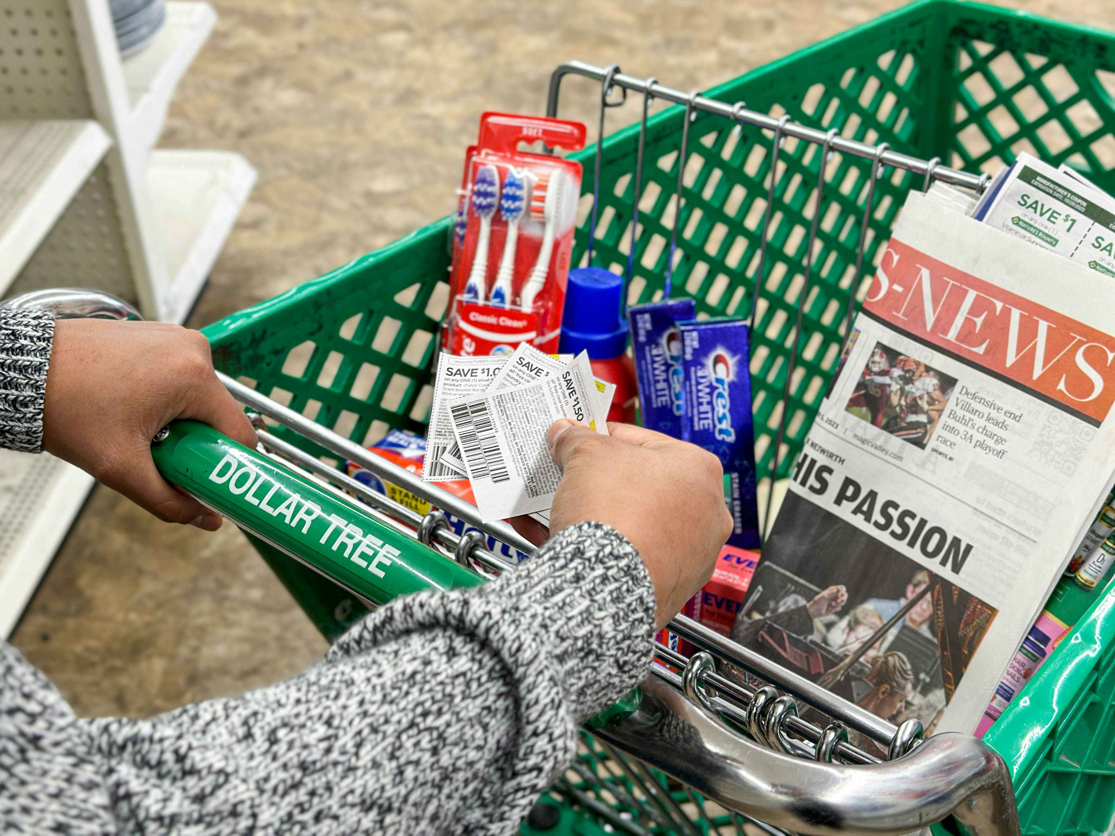 a person holding coupons next to items in dollar tree cart