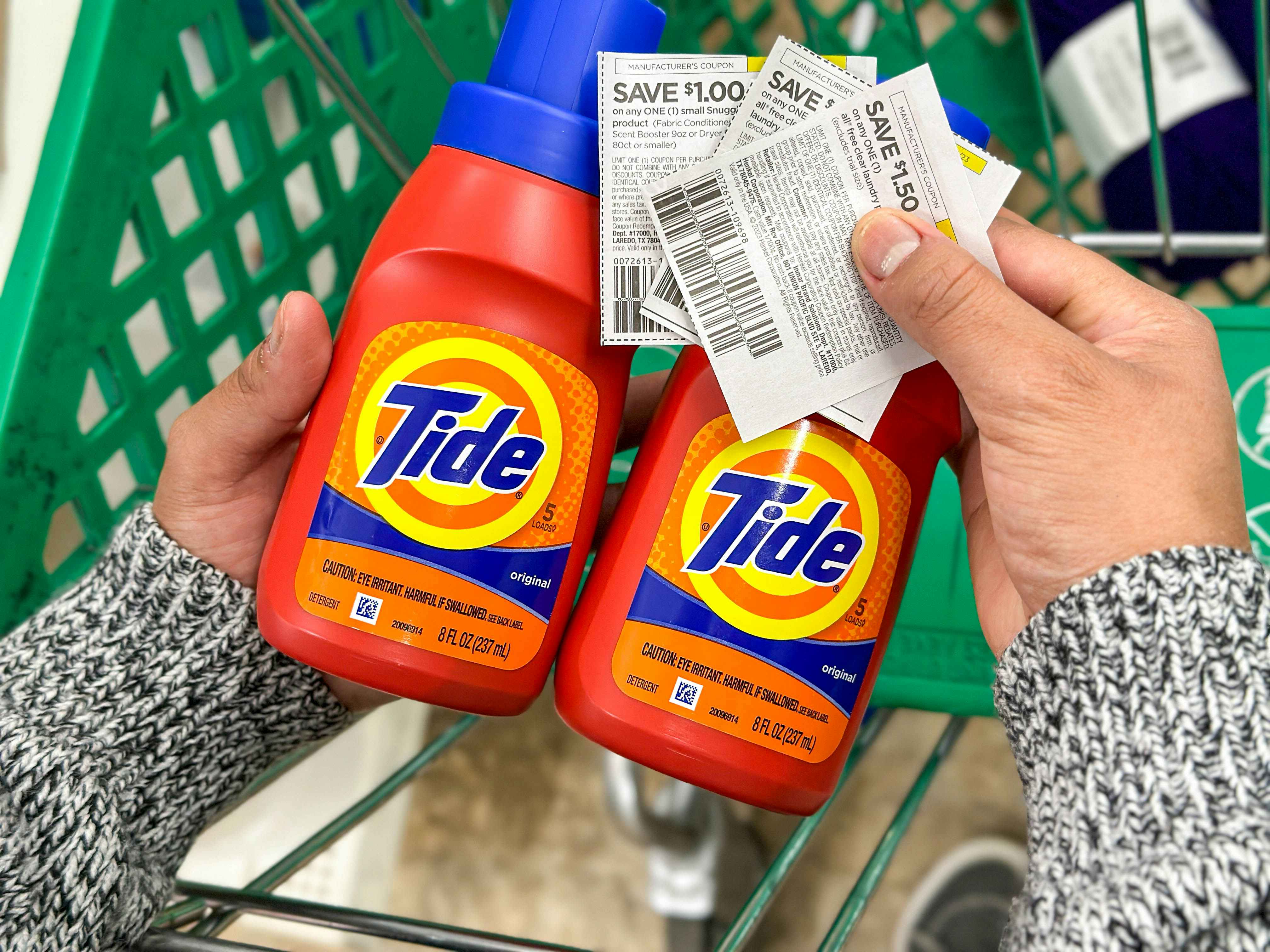 a person holding two tides and coupons in hand