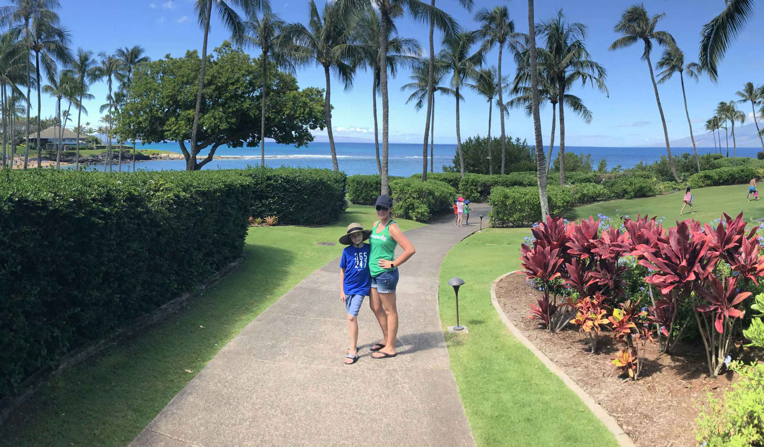 Woman and boy posing in front of the ocean in a tropical location.