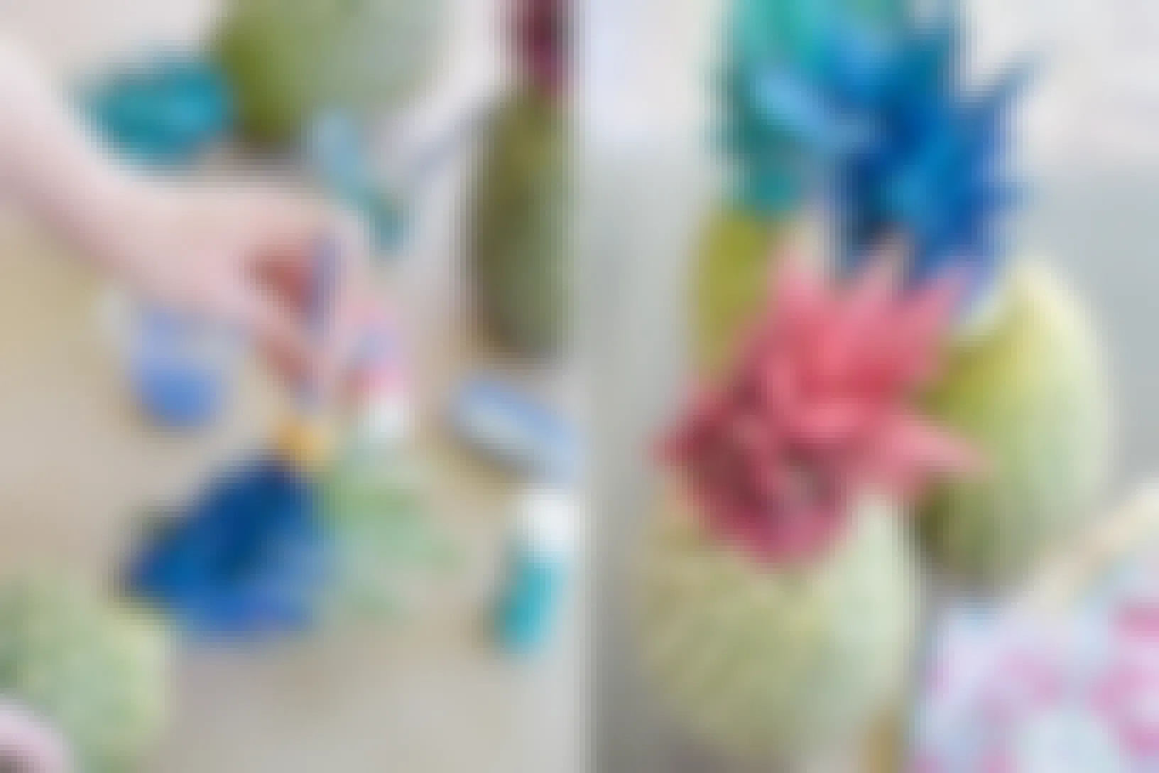 A person using acrylic paint to paint pineapple crowns next to some pineapples that have been painted pink and blue.