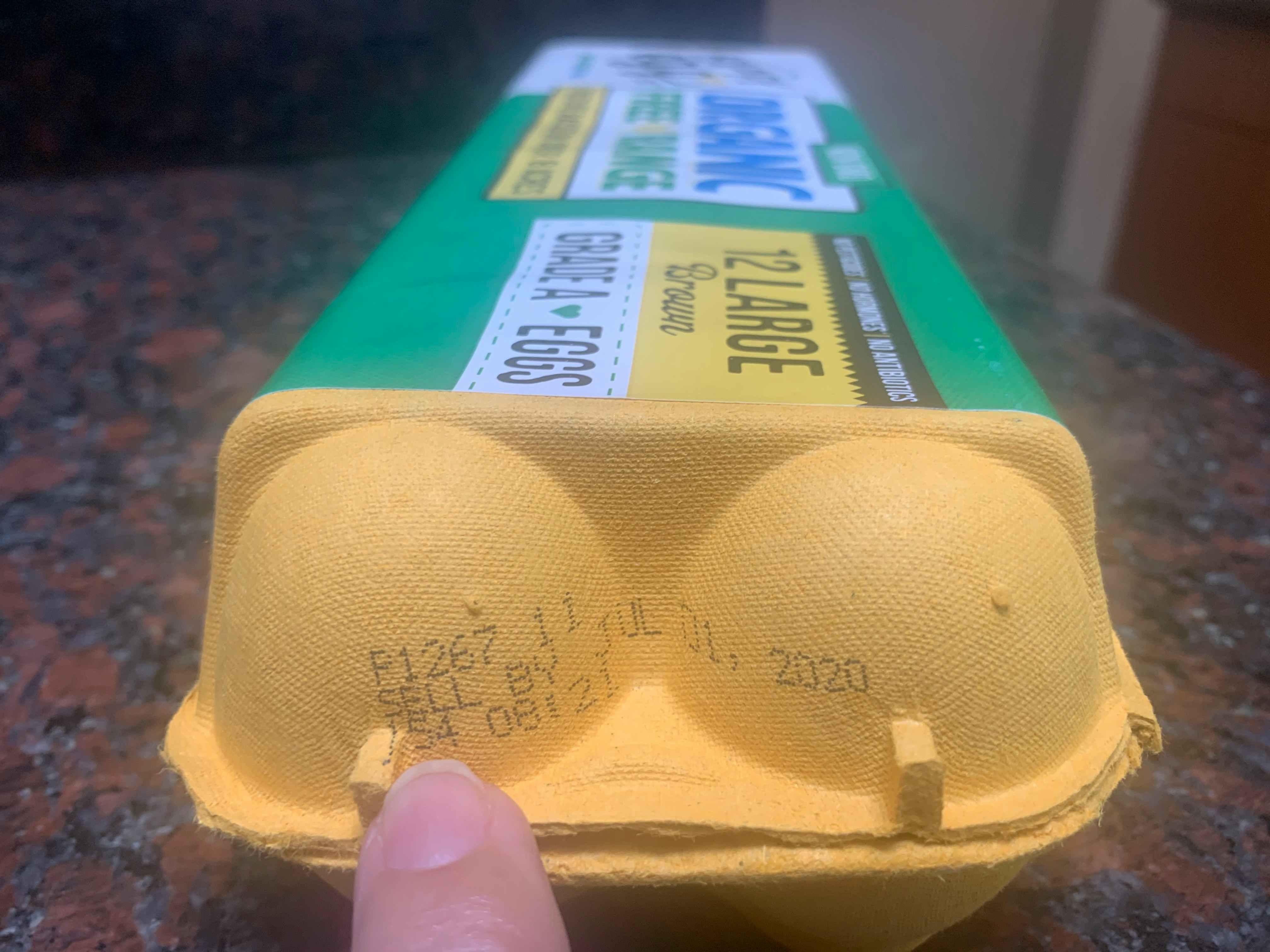 finger points to a sell by date stamped on egg carton