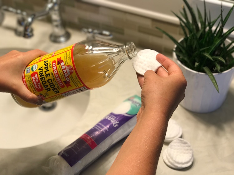 A woman applying apple cider vinegar to a cotton swab