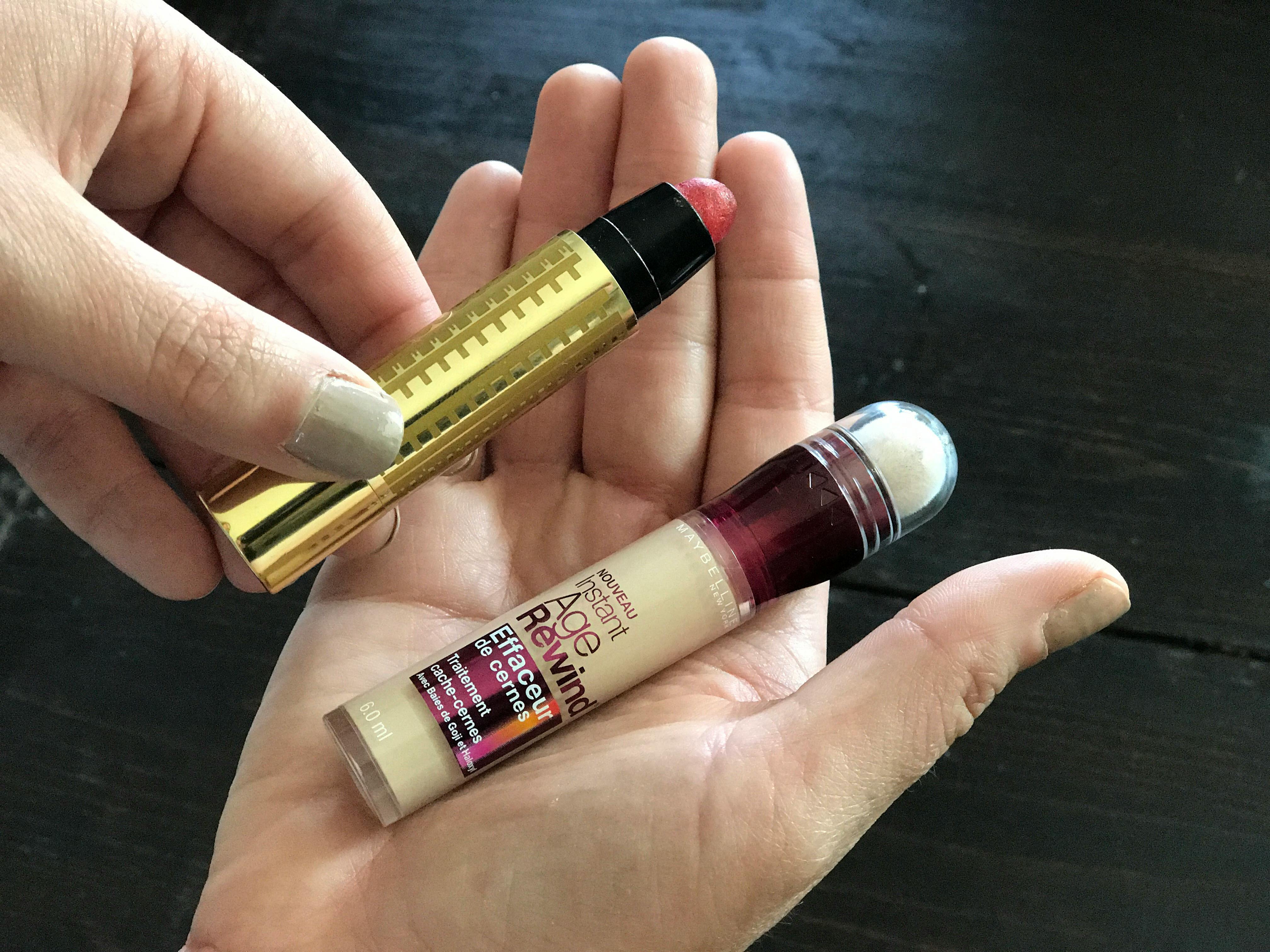 Hands holding pink lipstick and concealer