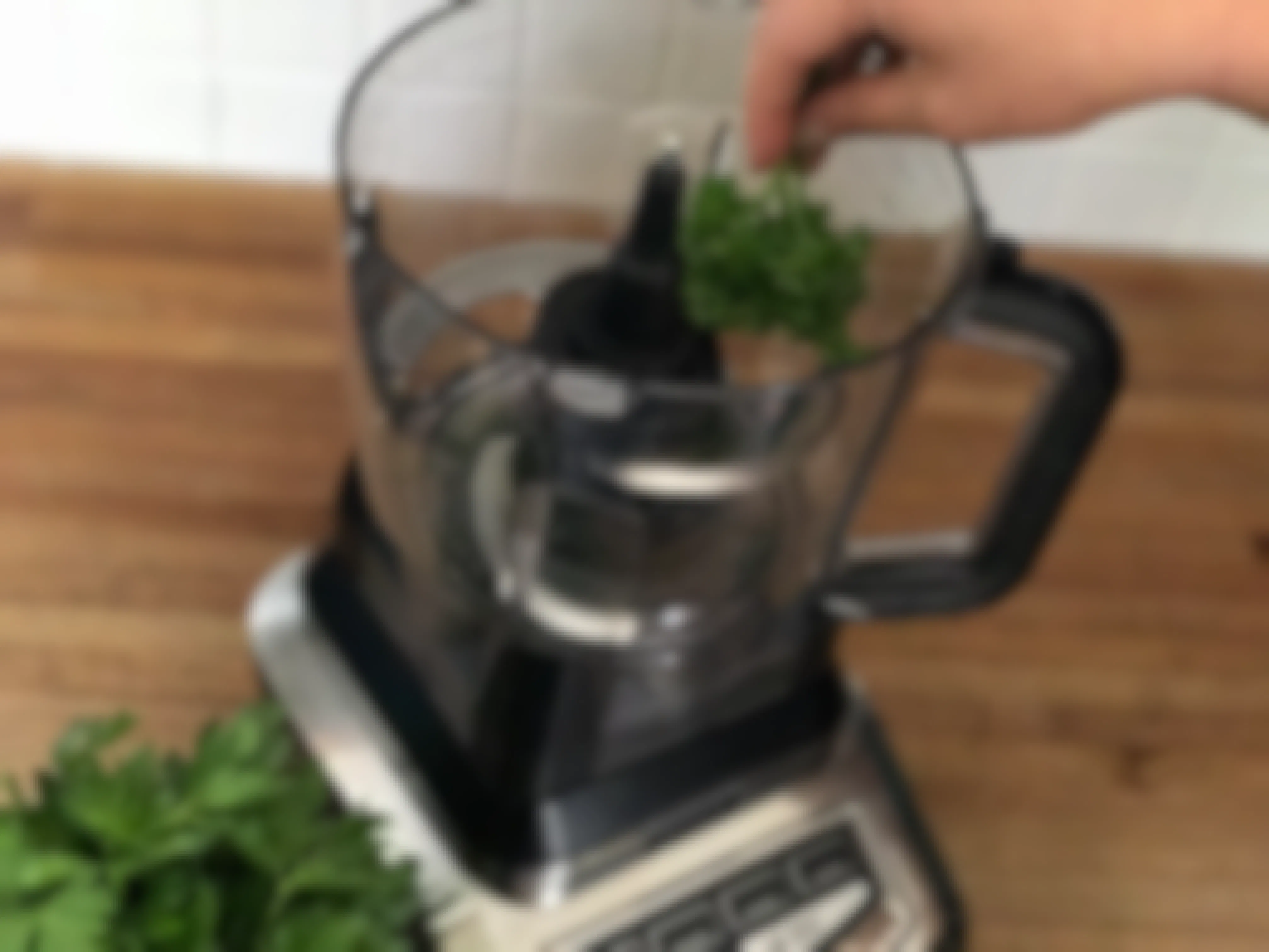 Parsley being tossed into a blender