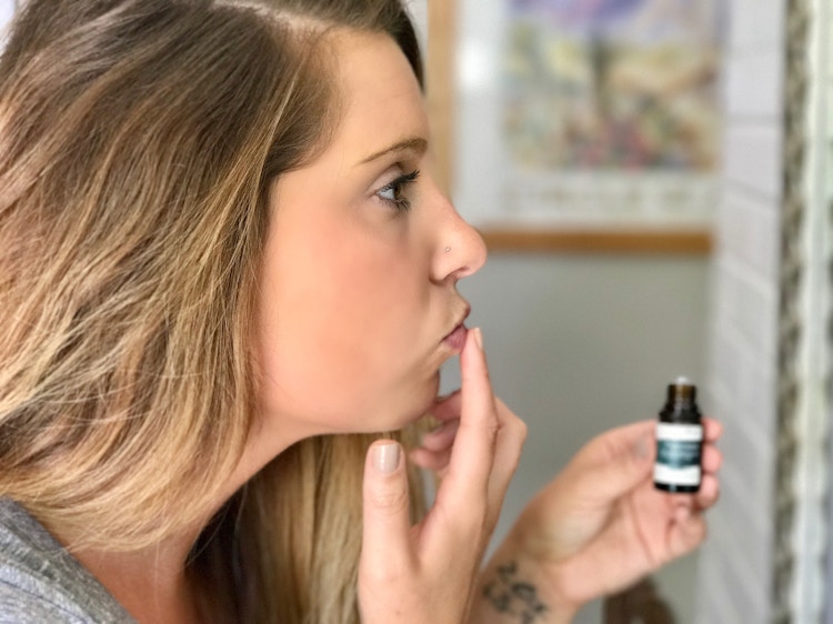Woman rubbing peppermint essential oil on her lips