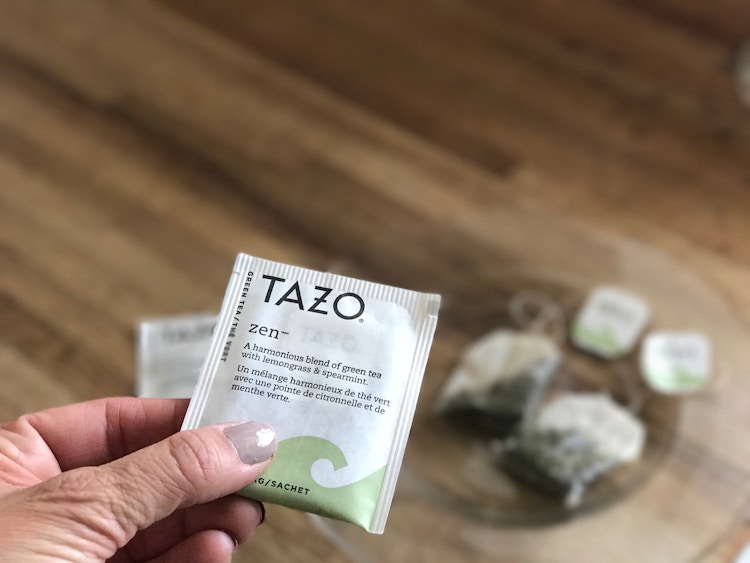 someone holding a Tazo zen green tea bag
