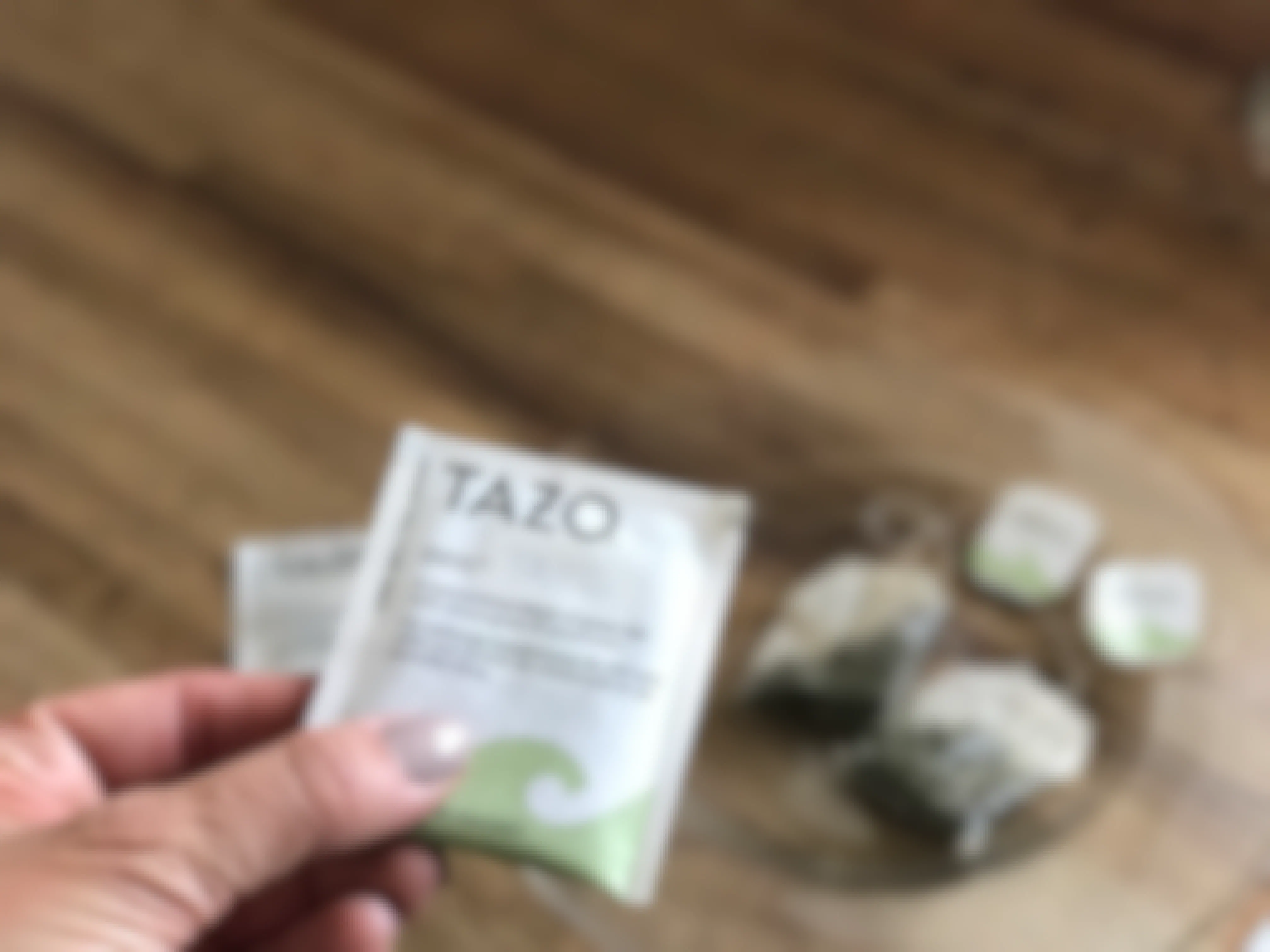 someone holding a Tazo zen green tea bag