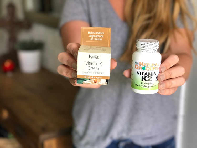 A woman holding vitamin K cream and vitamin k2 dietary supplements. 