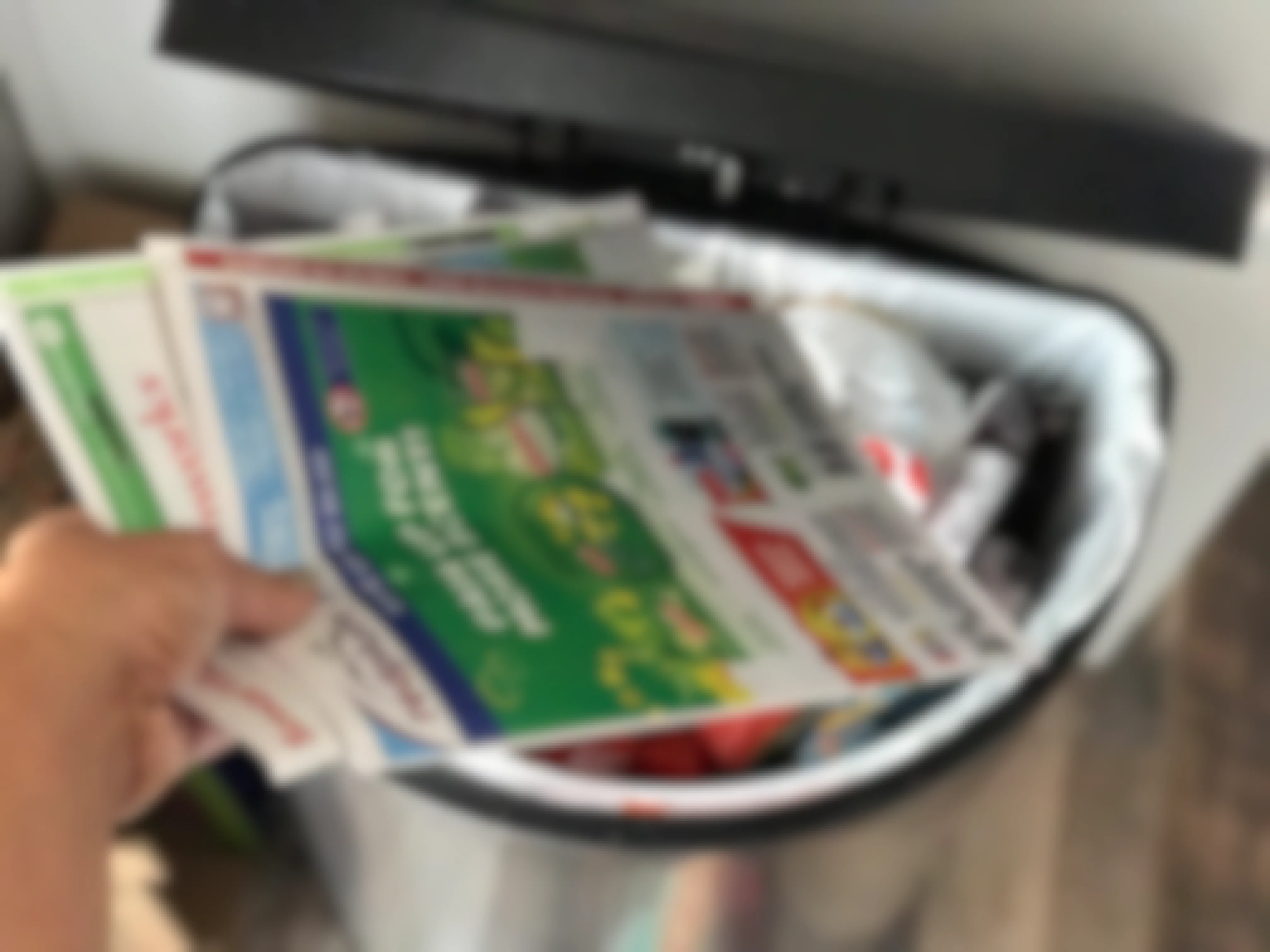 woman throwing paper coupon inserts in the trash