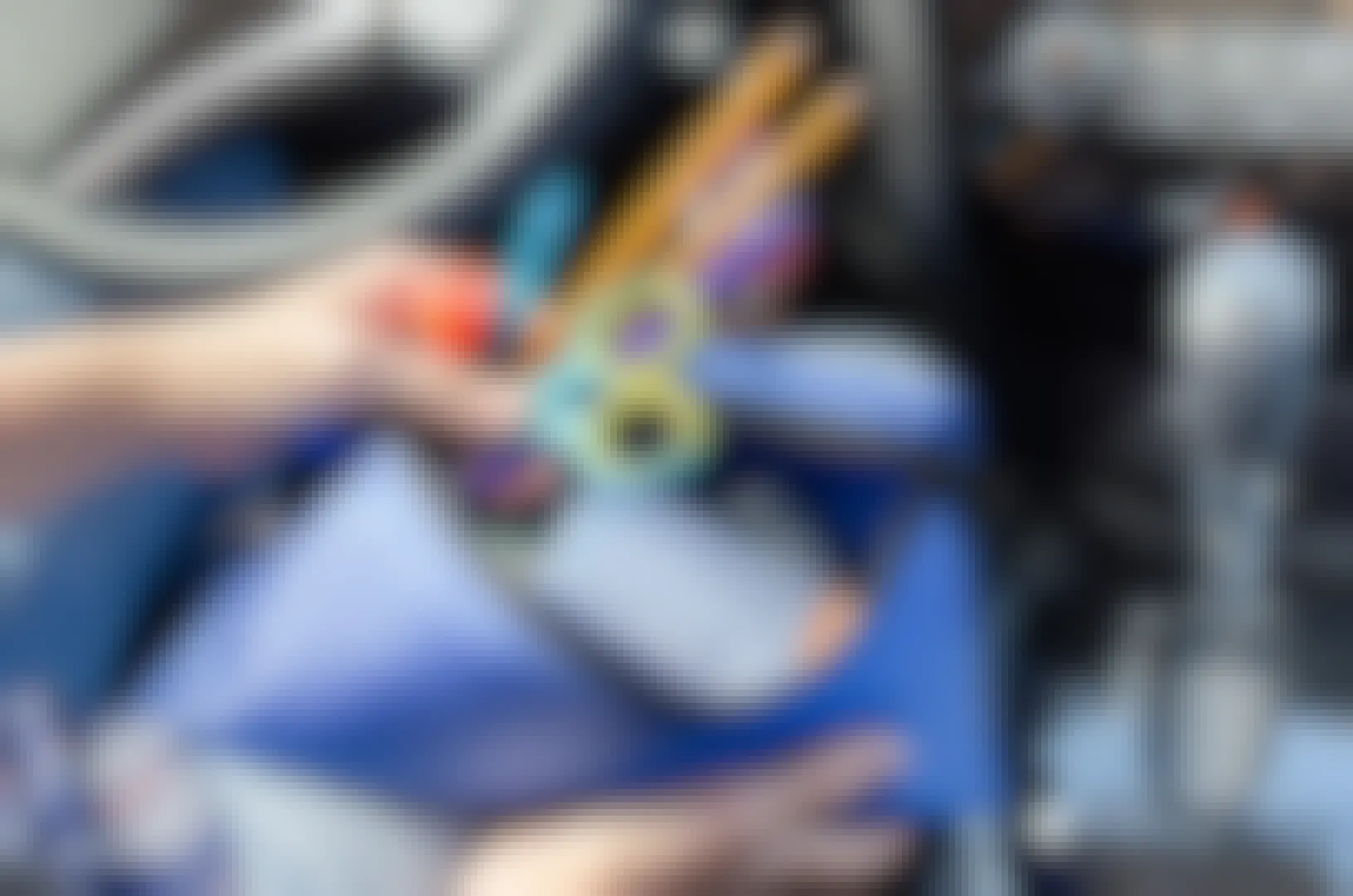 Person sitting in the front seat of a car pulling school supplies from a pencil case.