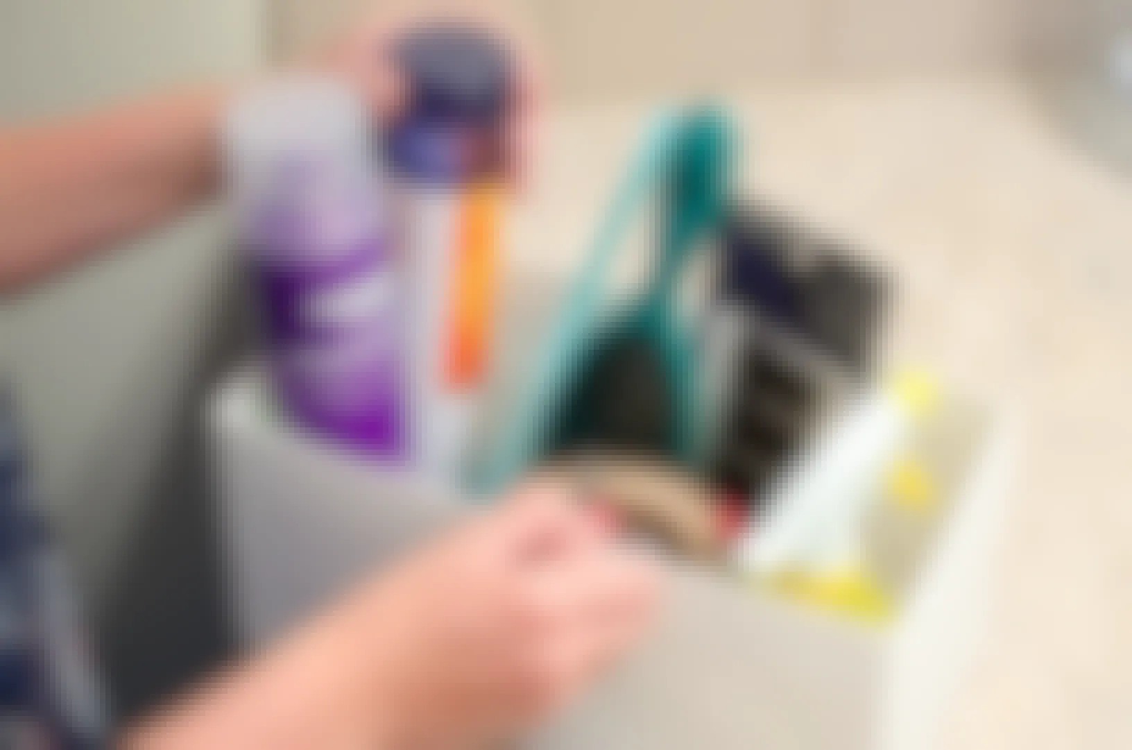 Woman pulling out hairspray from a bathroom organizer on a counter.