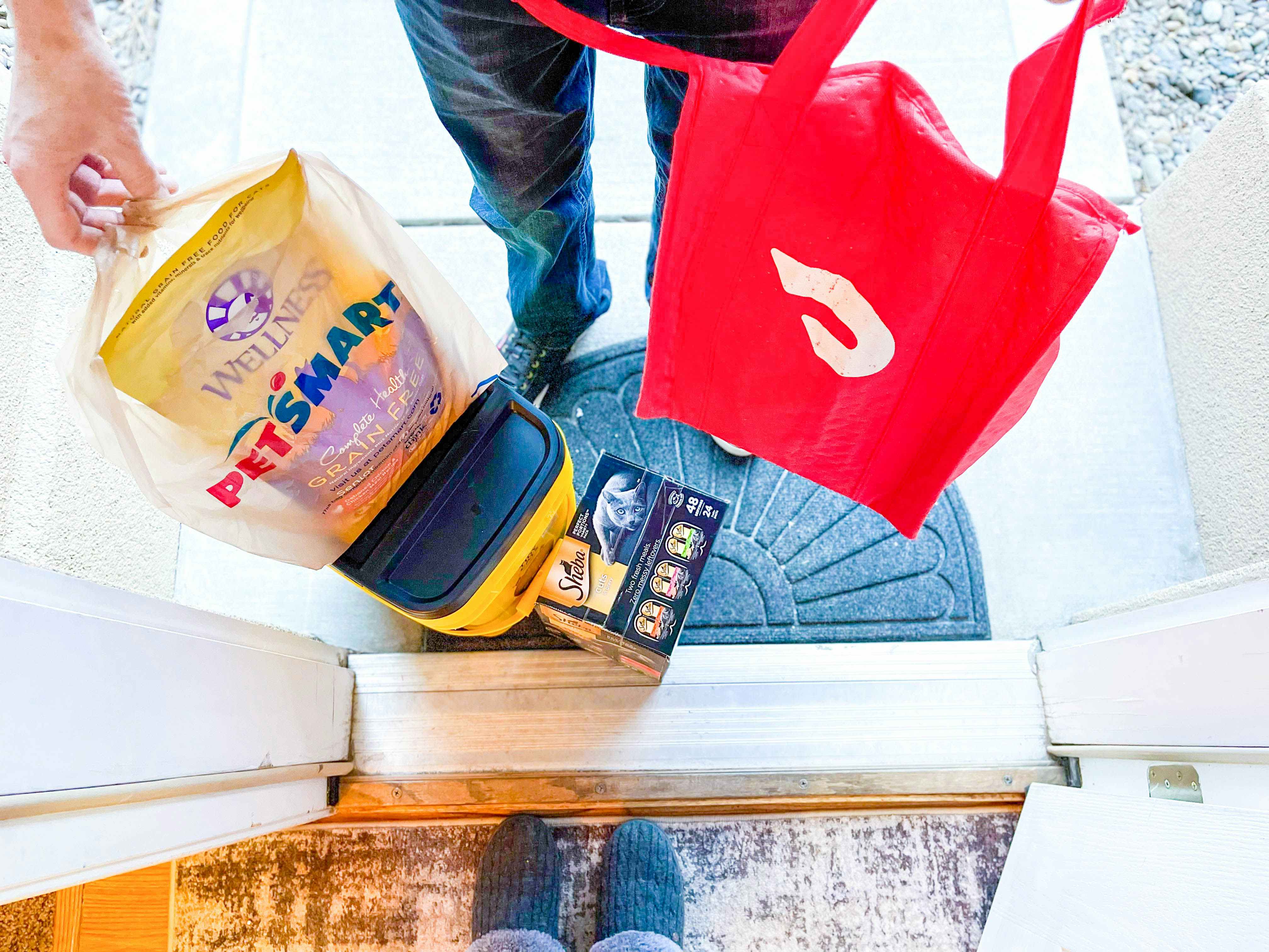 A Doordash delivery person dropping off a PetSmart delivery at a front door.