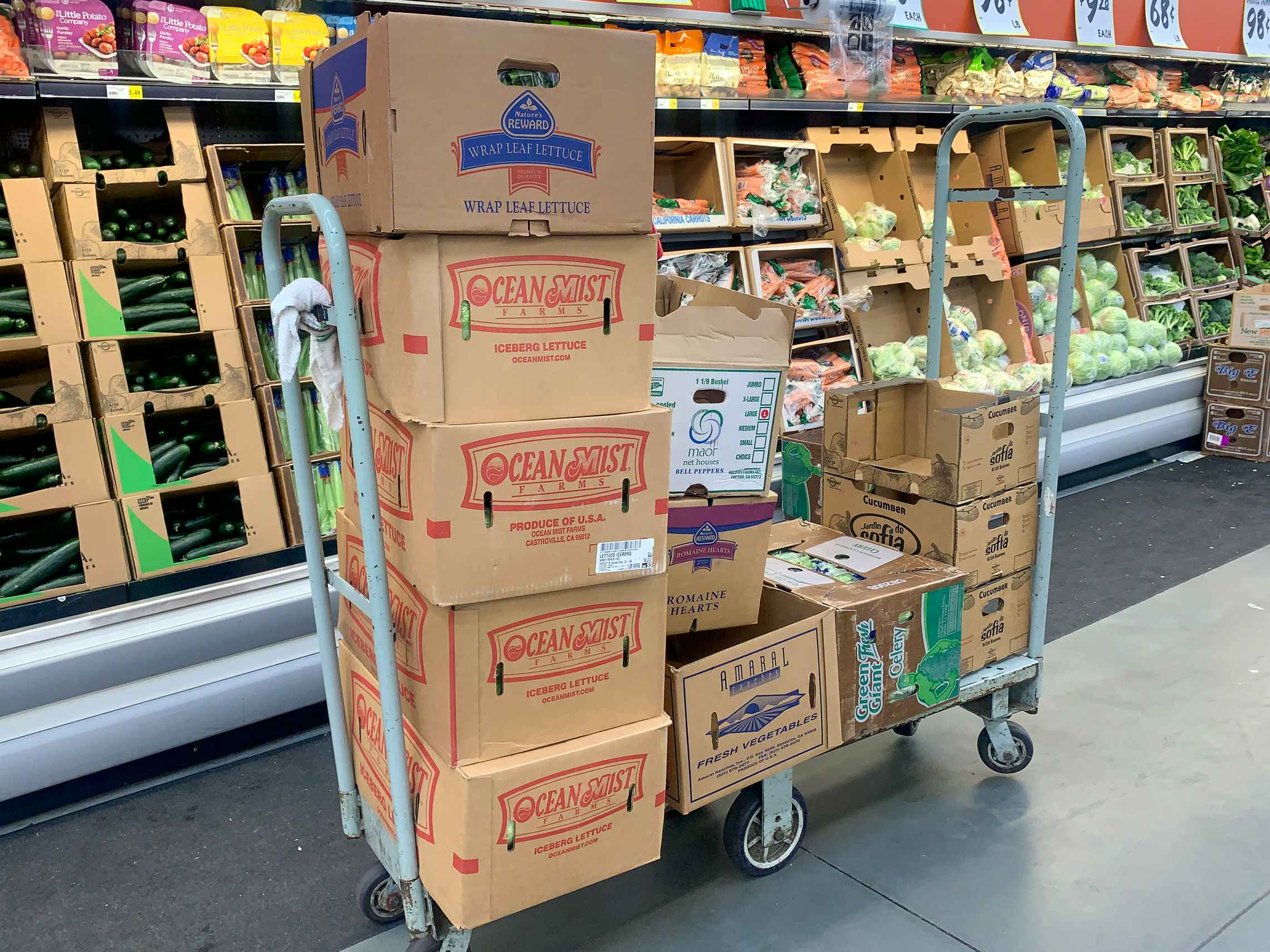 Cardboard produce boxes on a cart inside Winco.