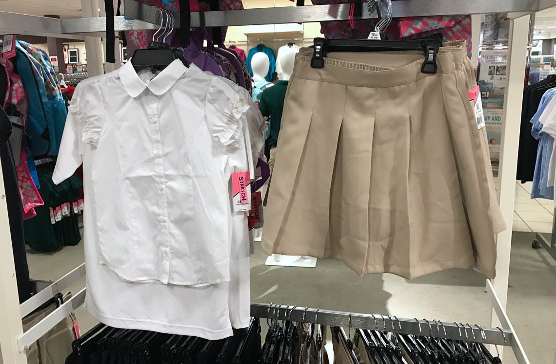A dressy girls uniform shirt and khaki uniform skirt hanging on a fixture inside JCPenney.