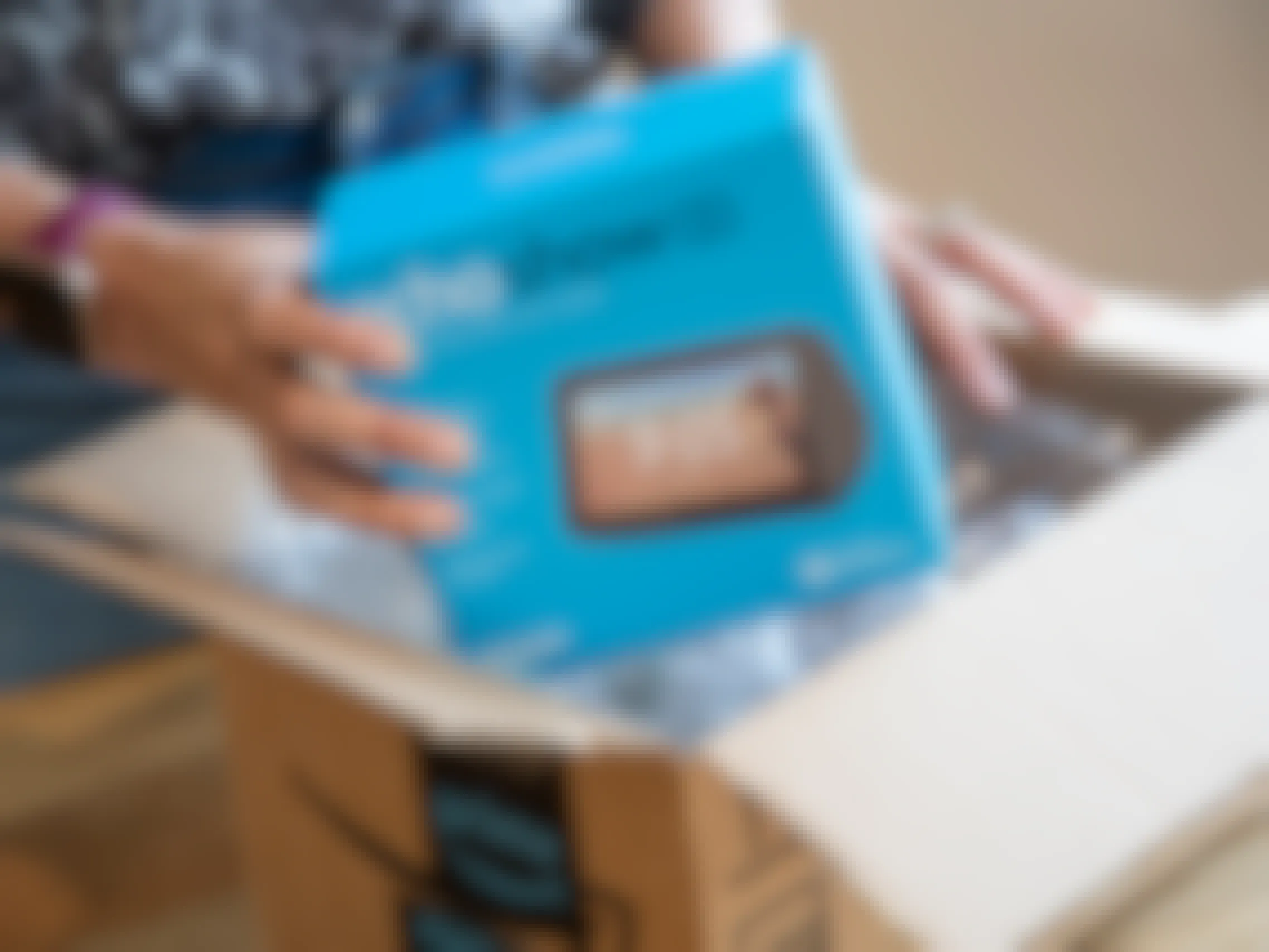 A person taking an Amazon Echo Show 5 out of an Amazon delivery box.