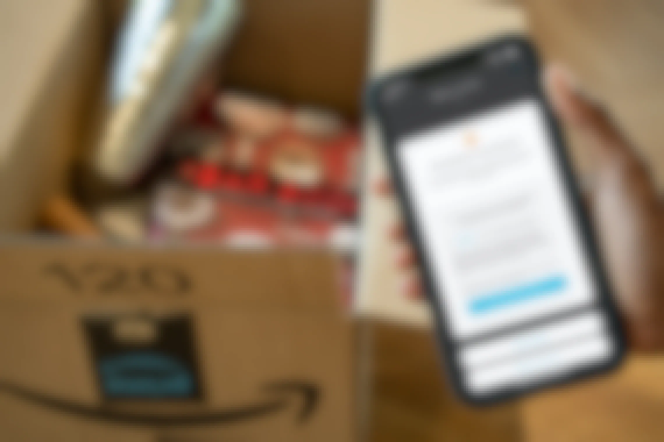 A person holding an iphone with the Paribus app next to an Amazon box.