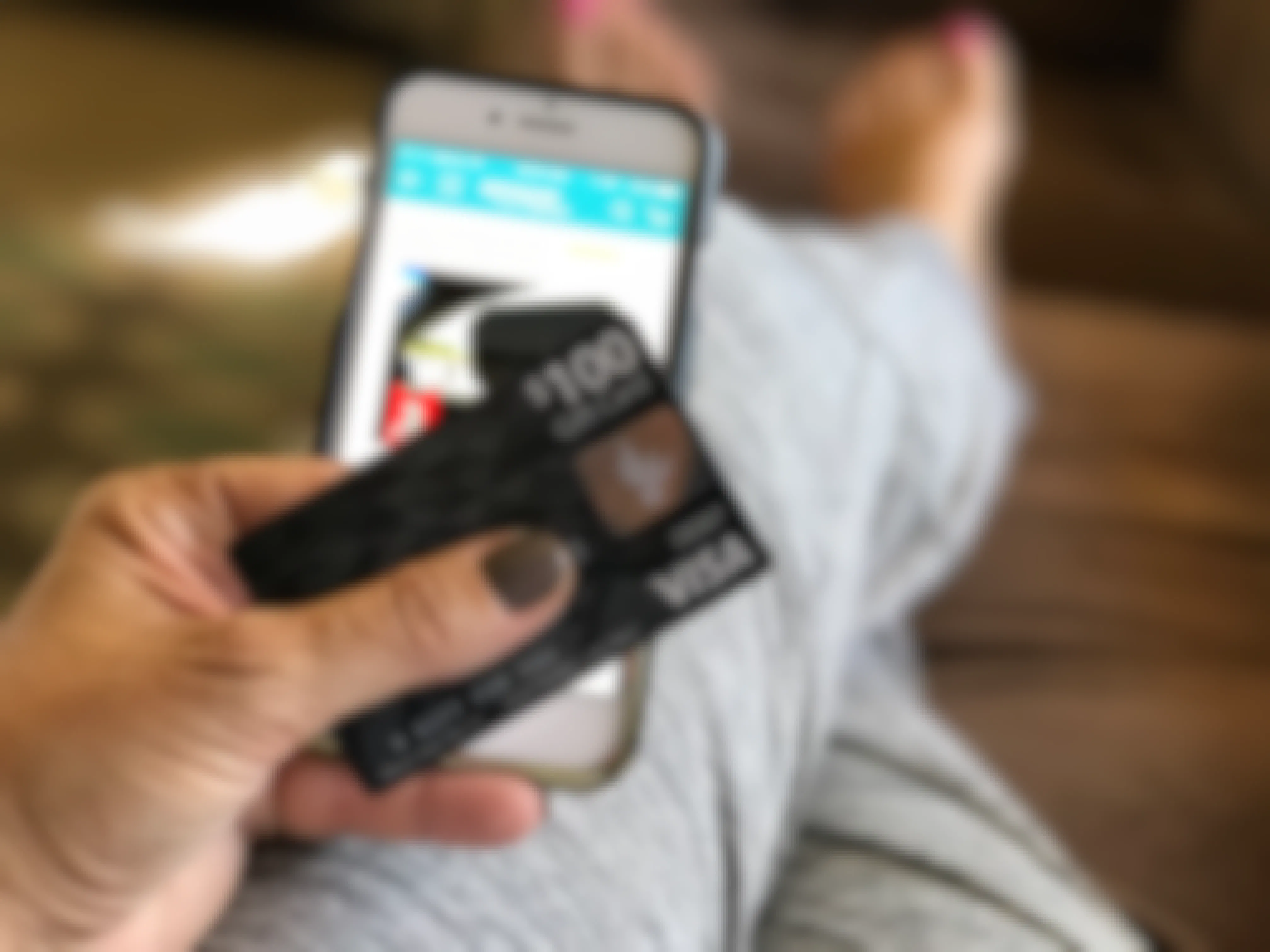 A person holding prepaid visa gift card next to phone with amazon app open