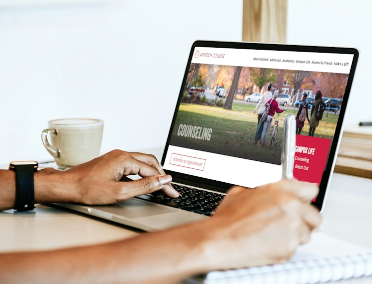 A student using a laptop to go on the Antioch College website.