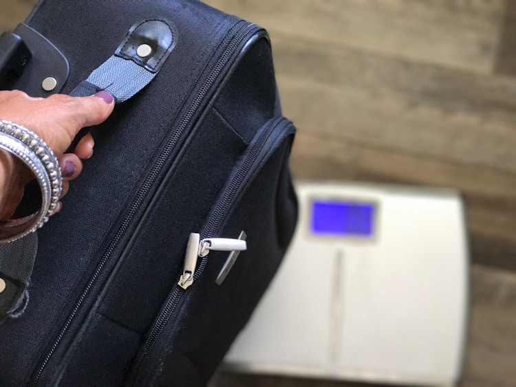 person placing packed suitcase on scale to check weight