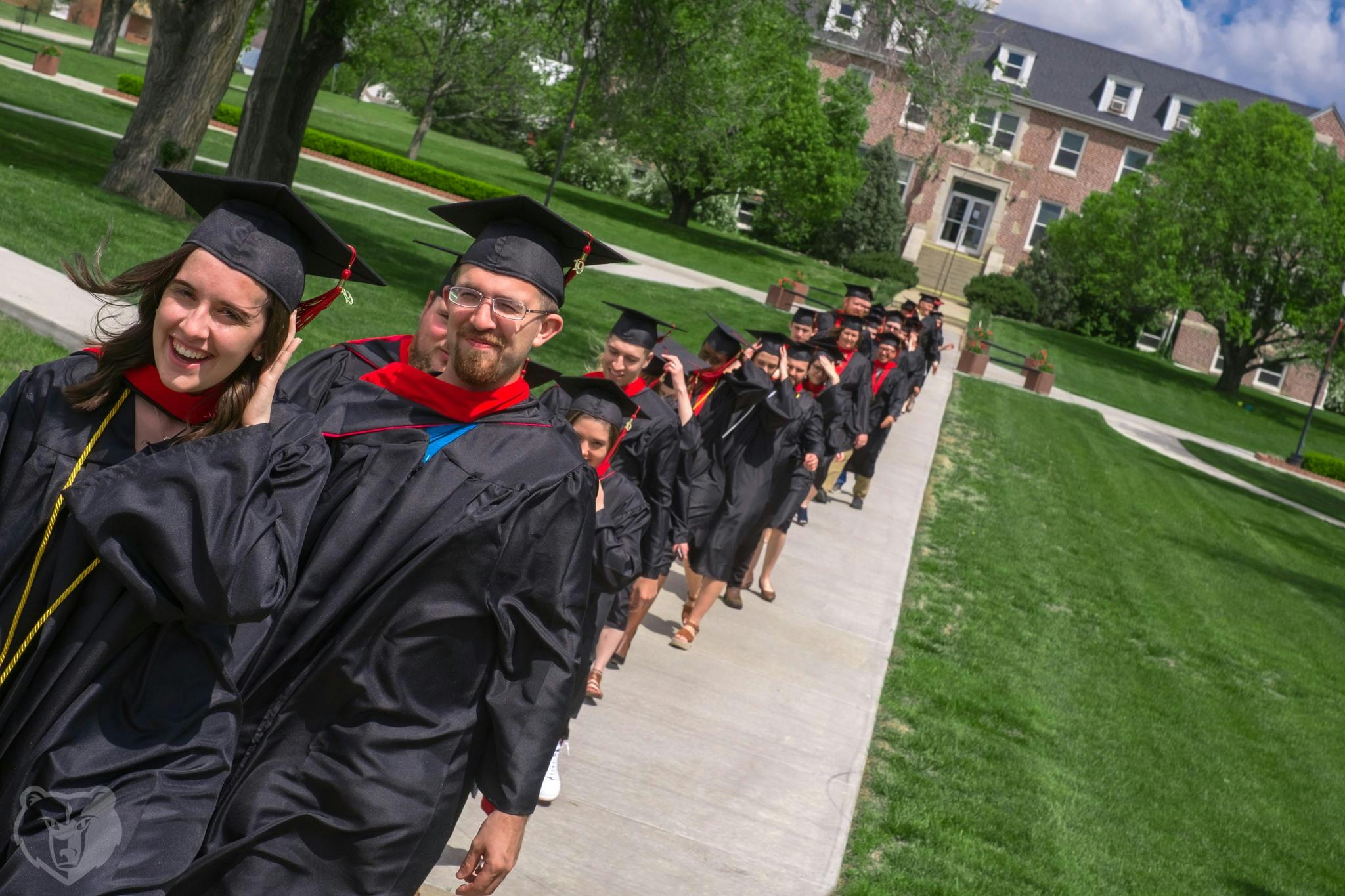 Students walking in a procession line wearing graduation caps and gowns at Barclay College.