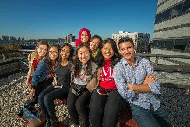 A group of students sitting together on a rooftop seating area at Macaulay Honors College.