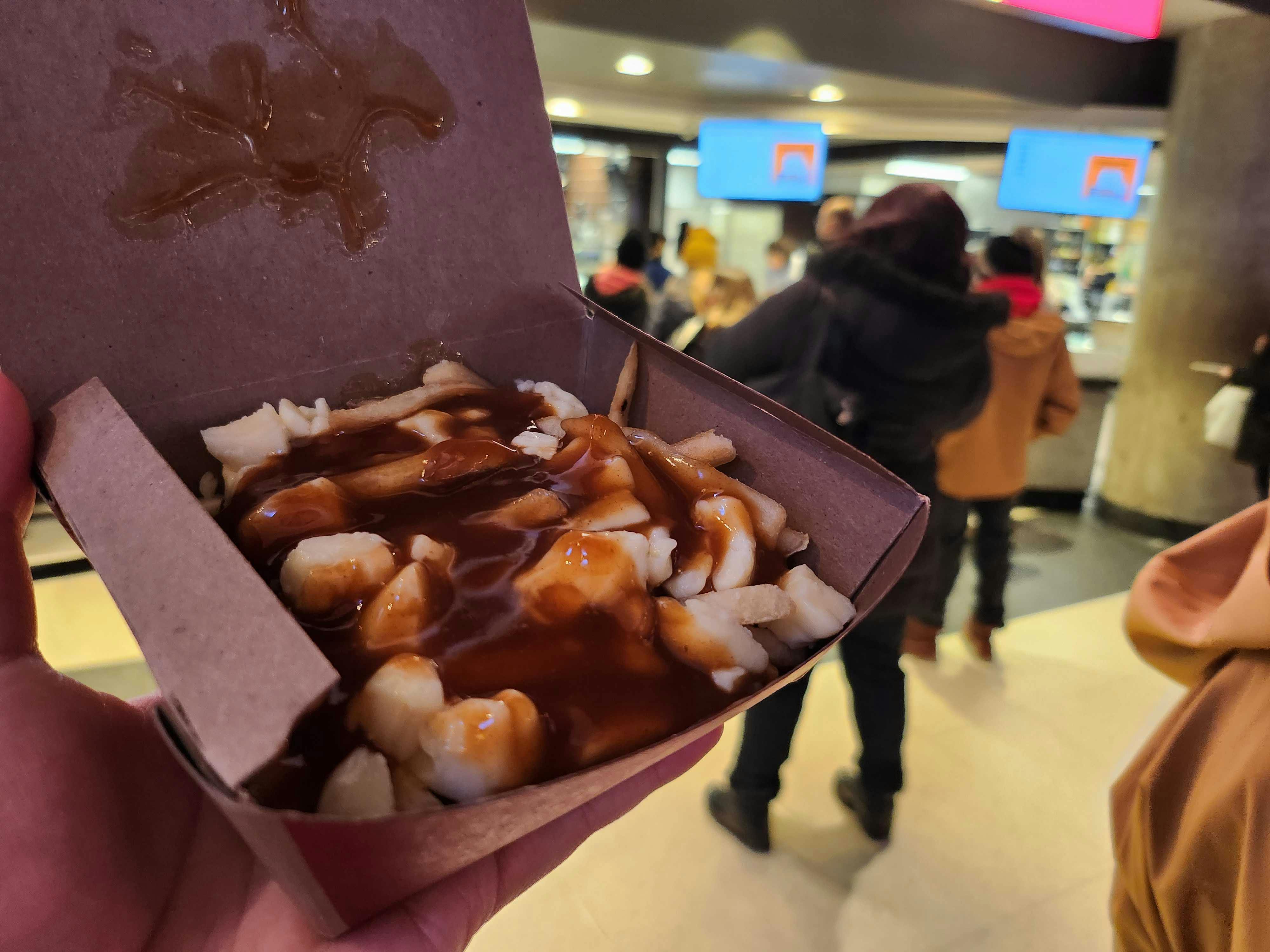 person holding mcdonalds poutine from canada