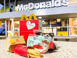 A 6-piece kids Happy Meal sitting on a table outside of a McDonald's storefront.