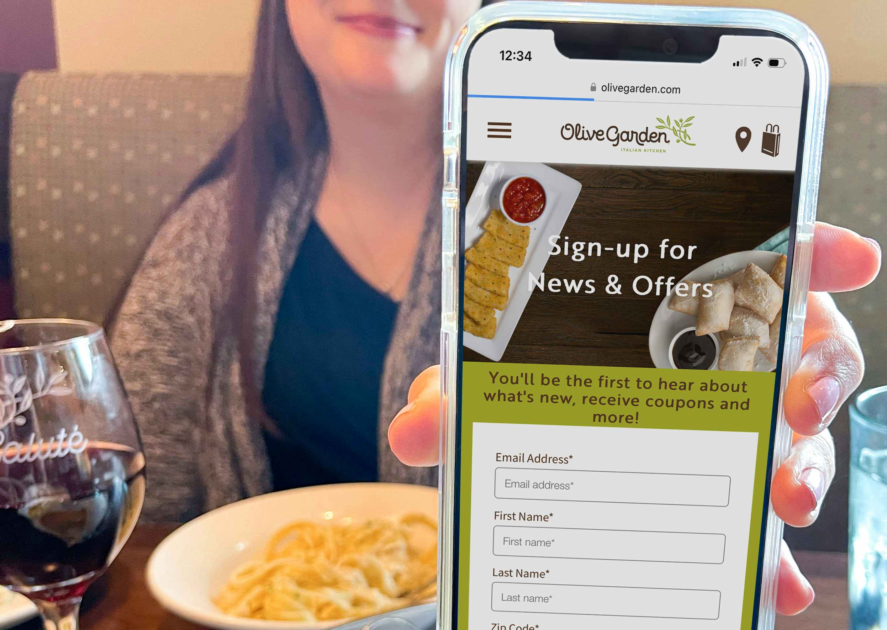 Someone holding their phone showing the Olive Garden eClub newsletter sign up page