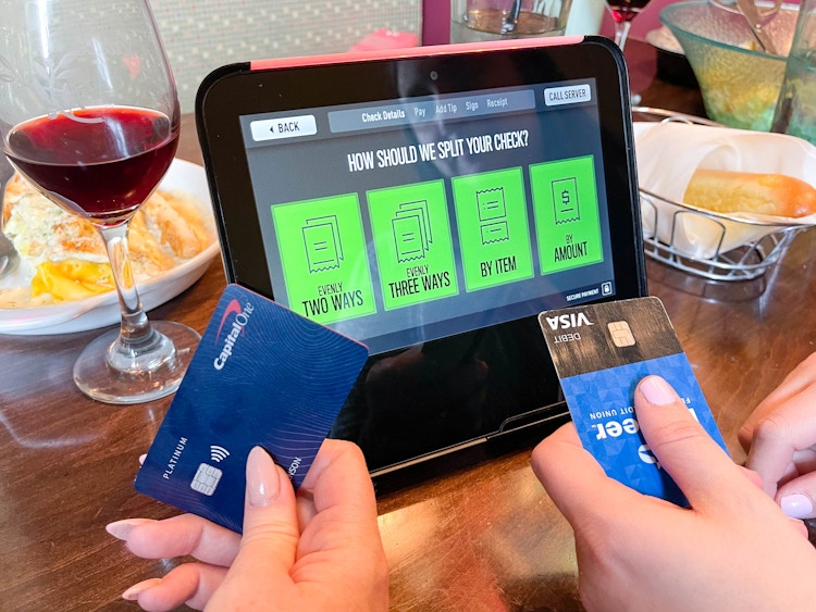 two people holding credit cards getting ready to pay split check on kiosk 