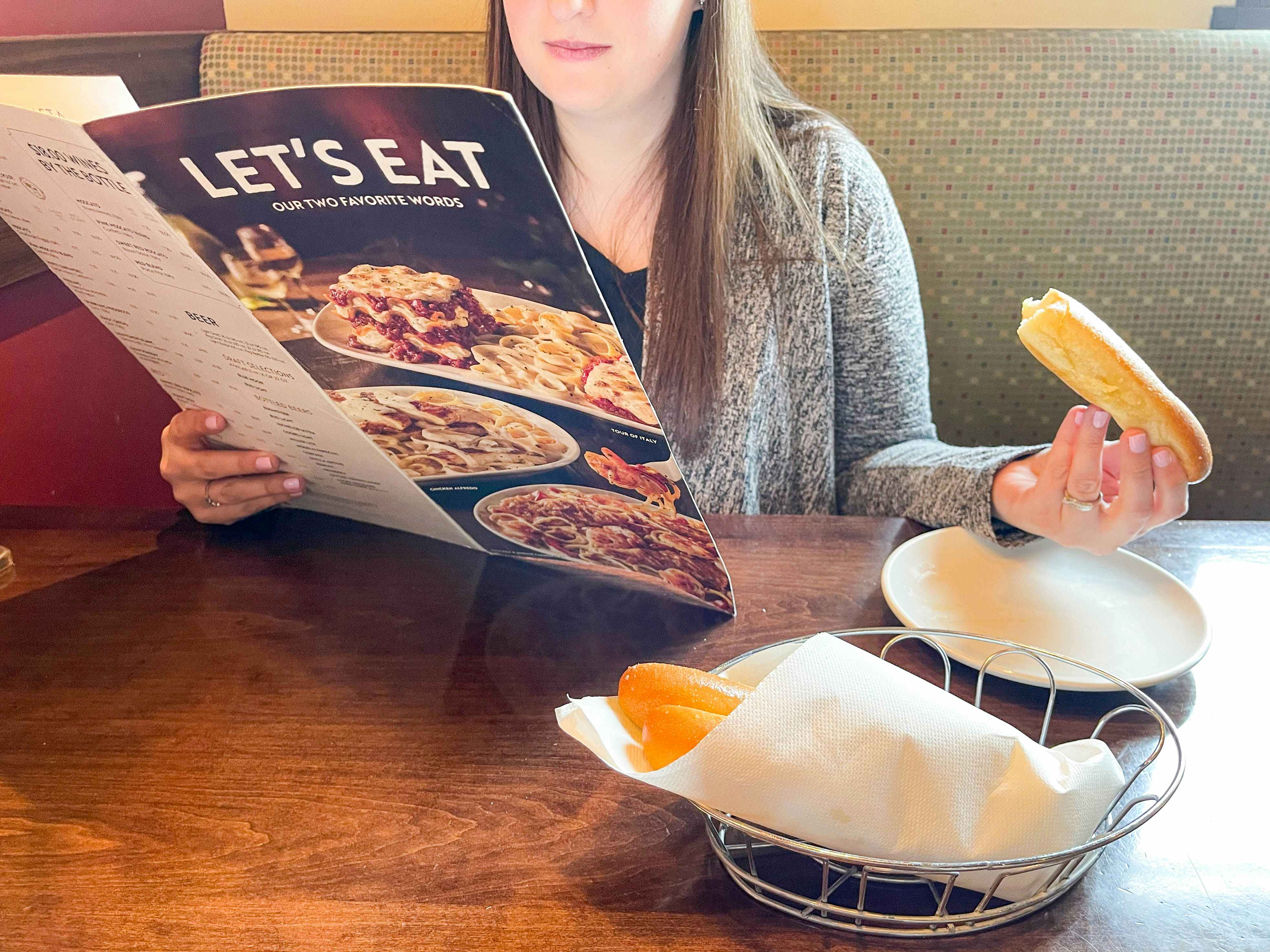 person looking at menu in restaurant and eating breadsticks