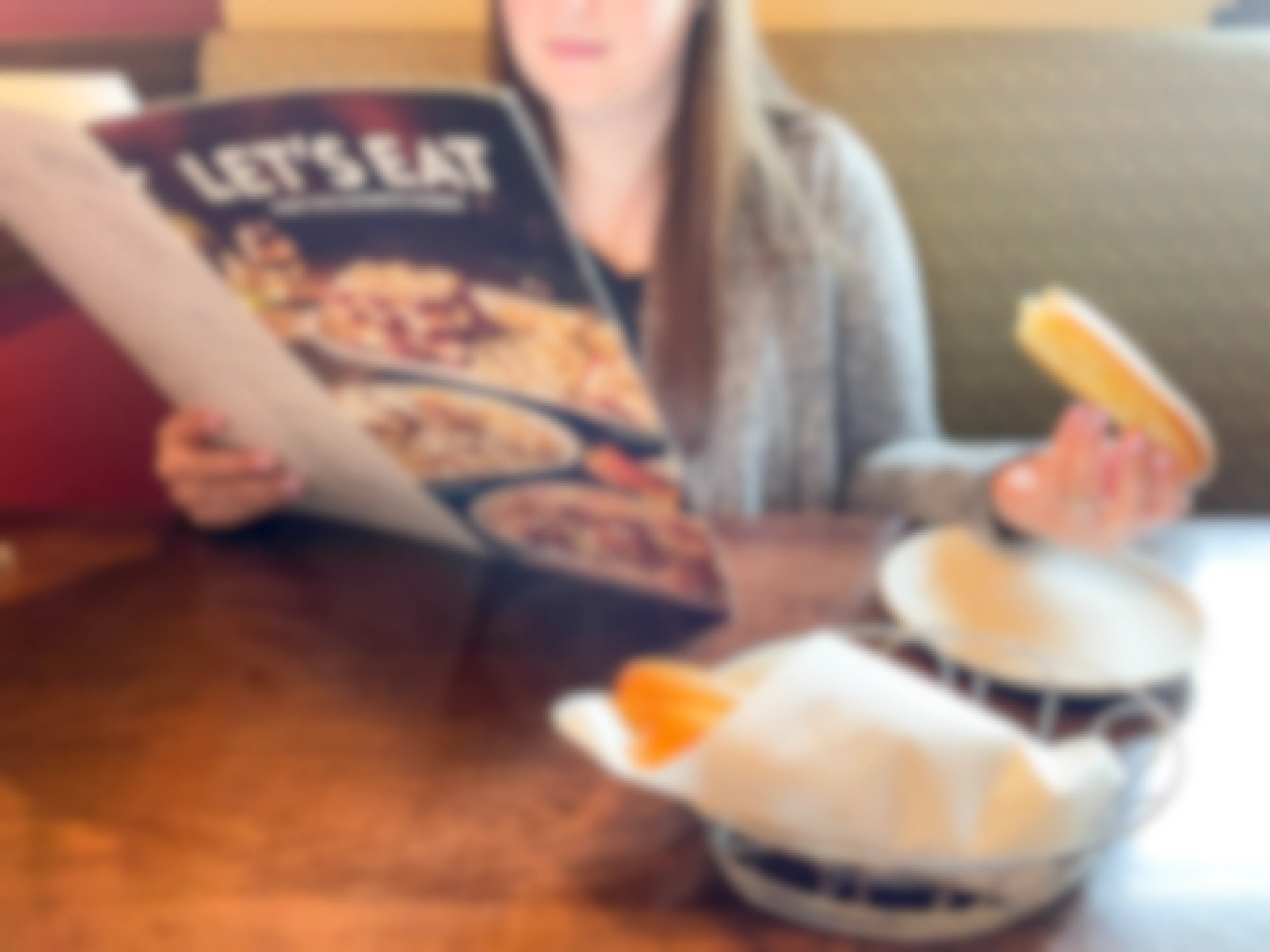 person looking at menu in restaurant and eating breadsticks