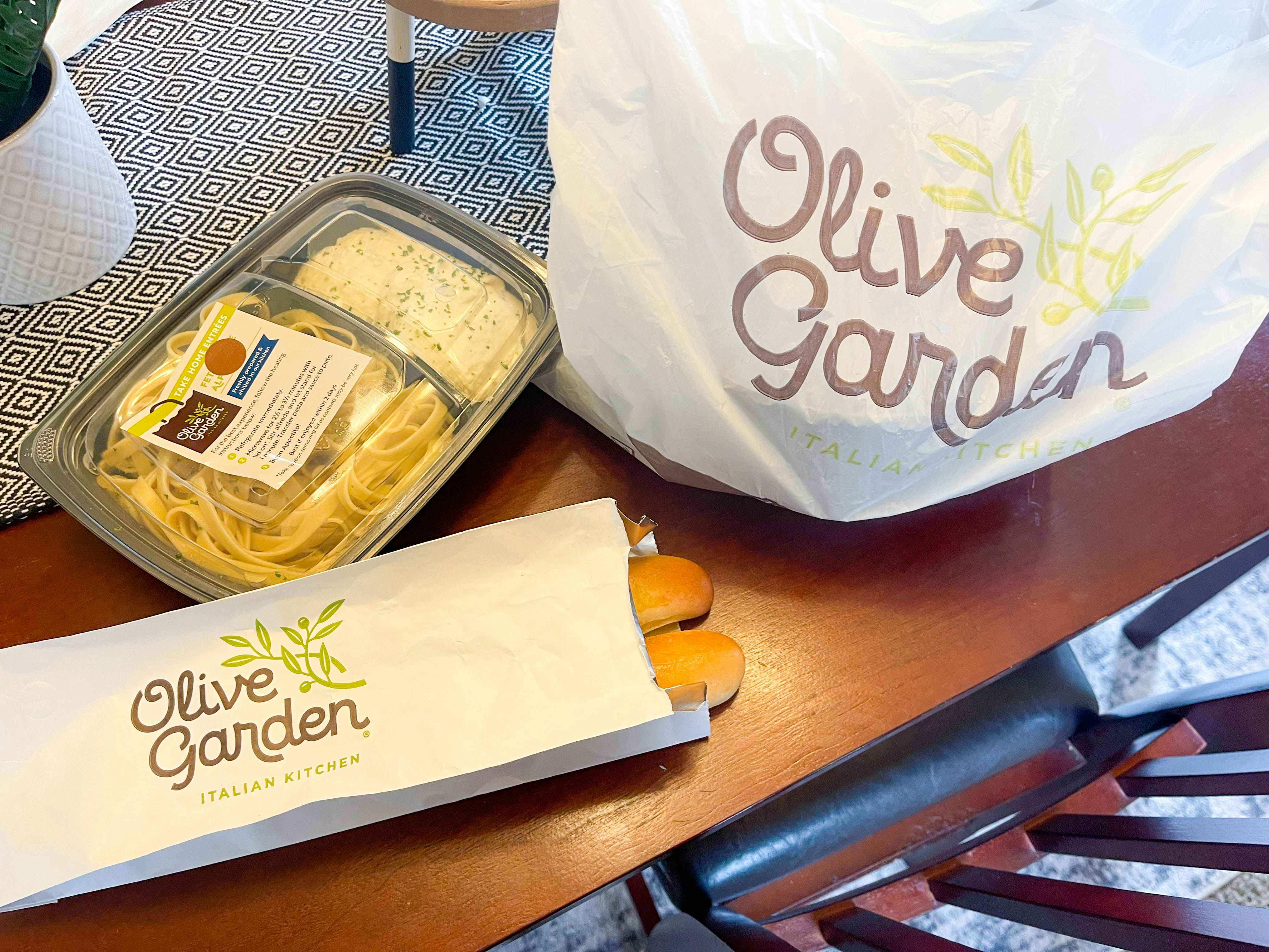 A to-go order from Olive Garden on a dining room table.