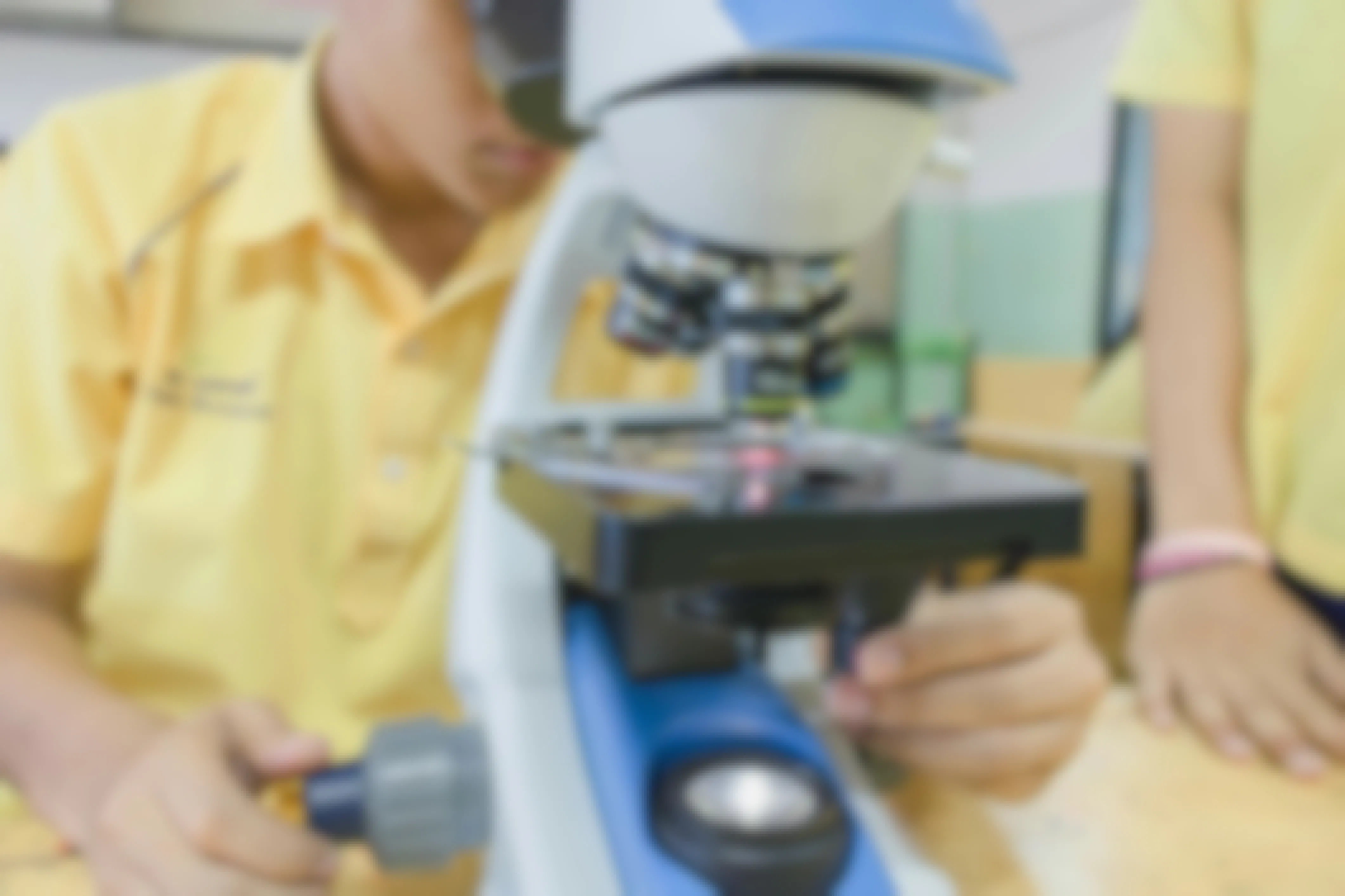 A student in a science lab looking through a microscope.