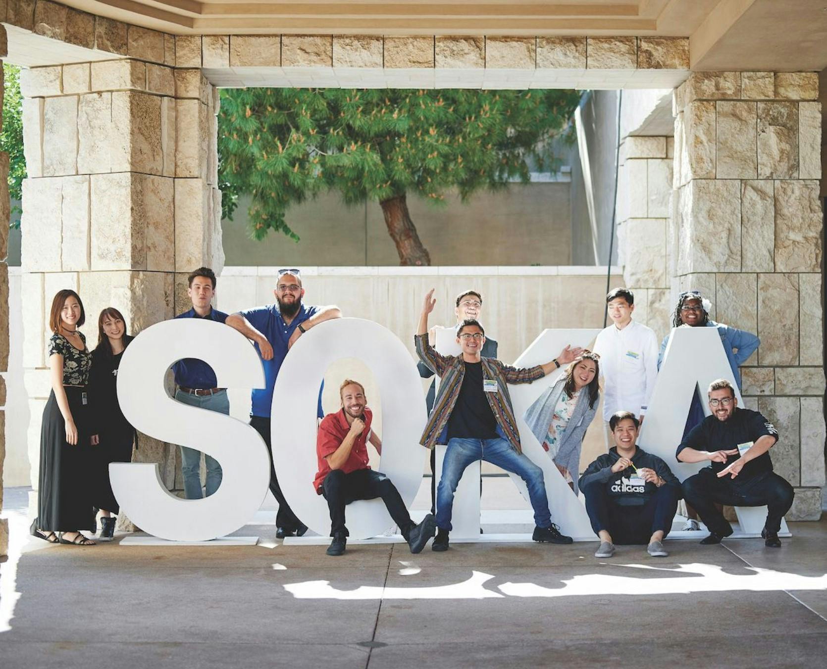 Students in front of large letters spelling out SOKA on Soka University's campus.
