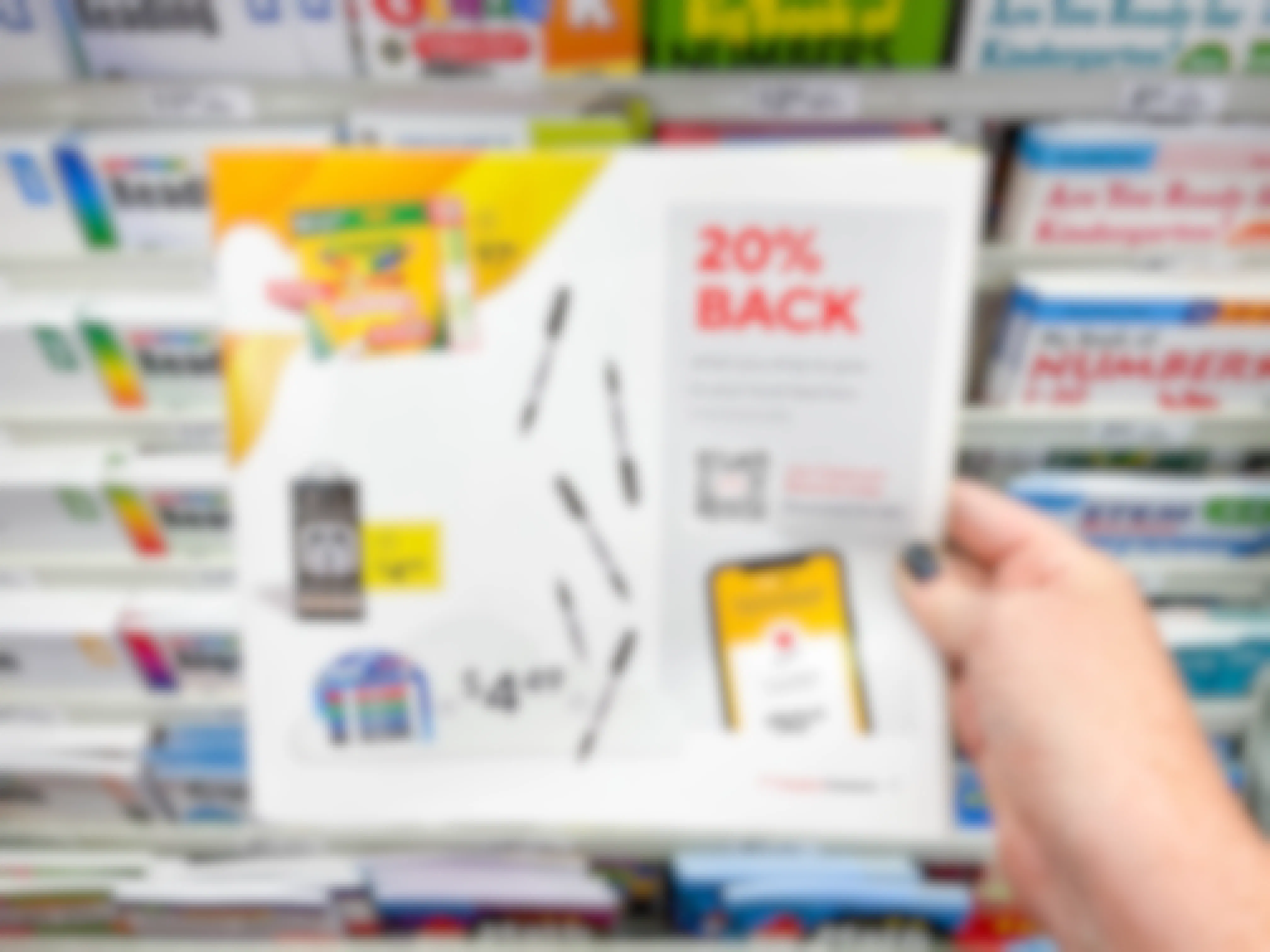 A person's hand holding up a paper advertisement for Classroom Rewards at Staples.