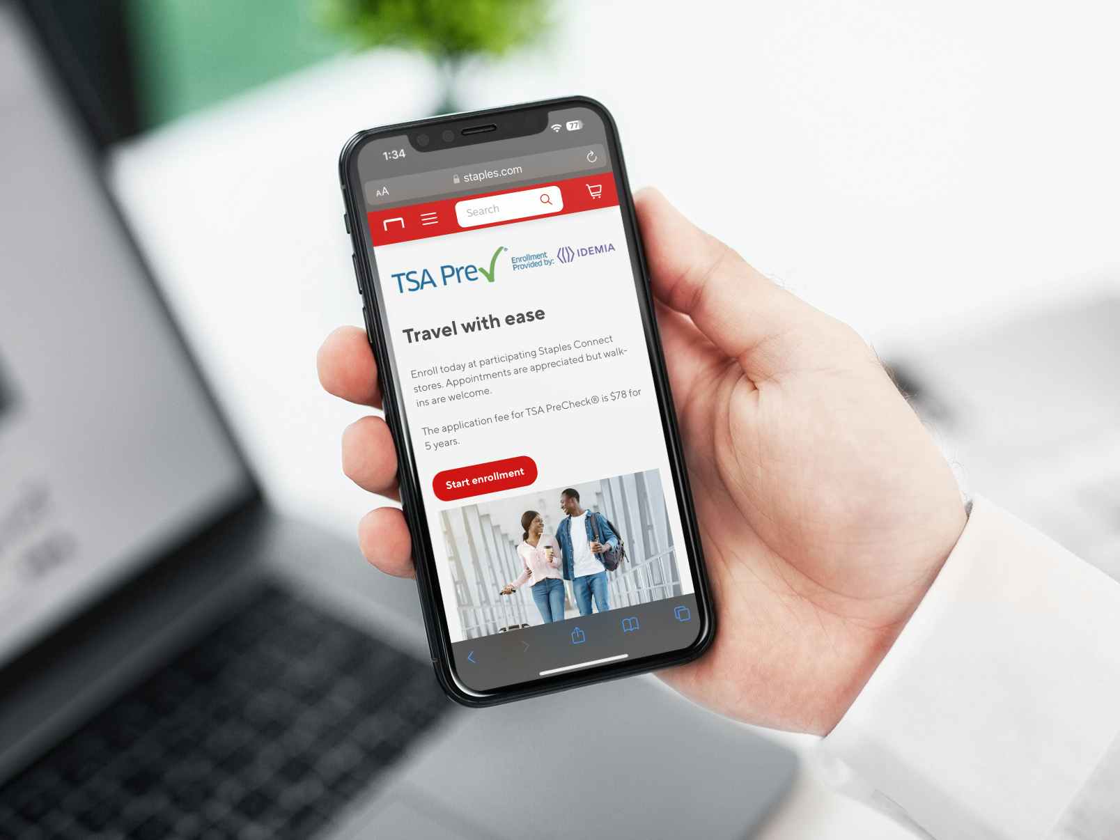 Someone holding a phone displaying the webpage on Staples.com about TSA Precheck enrollment