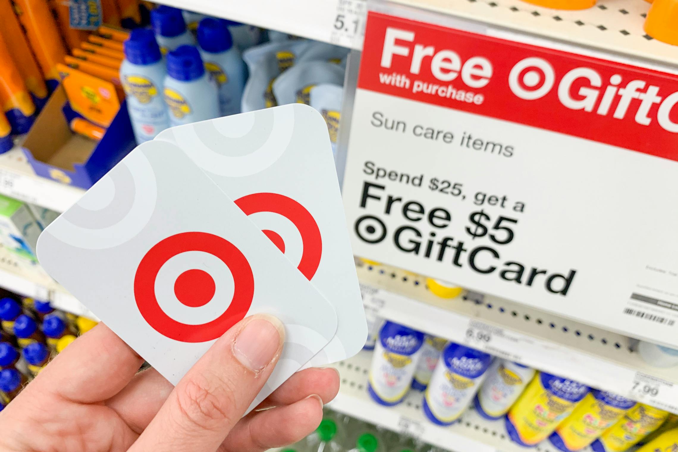 person holding two target gift cards next to free signage