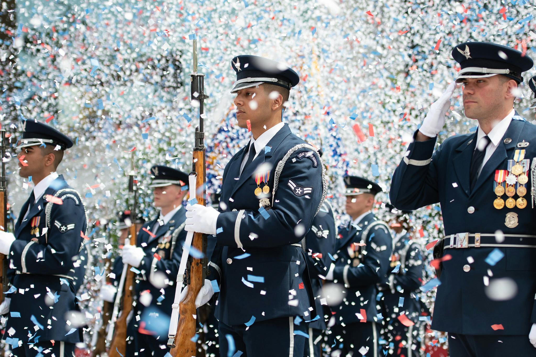 US Air Force soldiers dressed in full dress uniform with confetti flying around them.