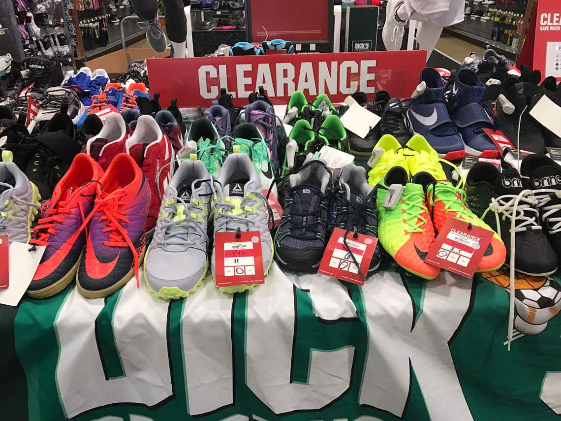 A clearance table filled with running shoes and cleats at Dicks Sporting Goods