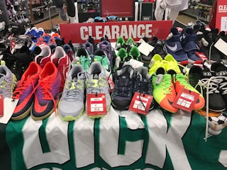 A clearance table filled with running shoes and cleats at Dicks Sporting Goods