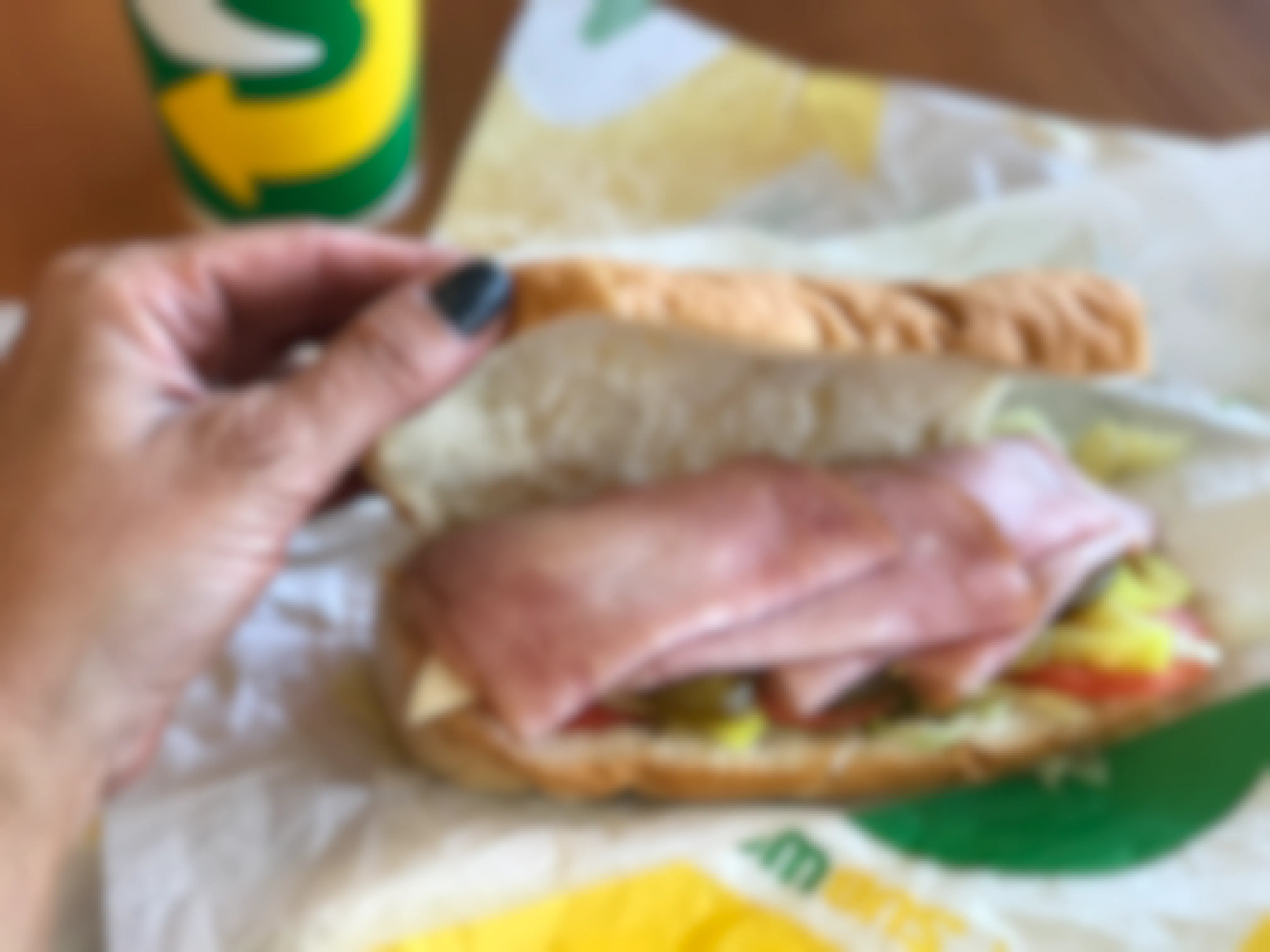 woman's hand opens a subway sub to reveal ingredients