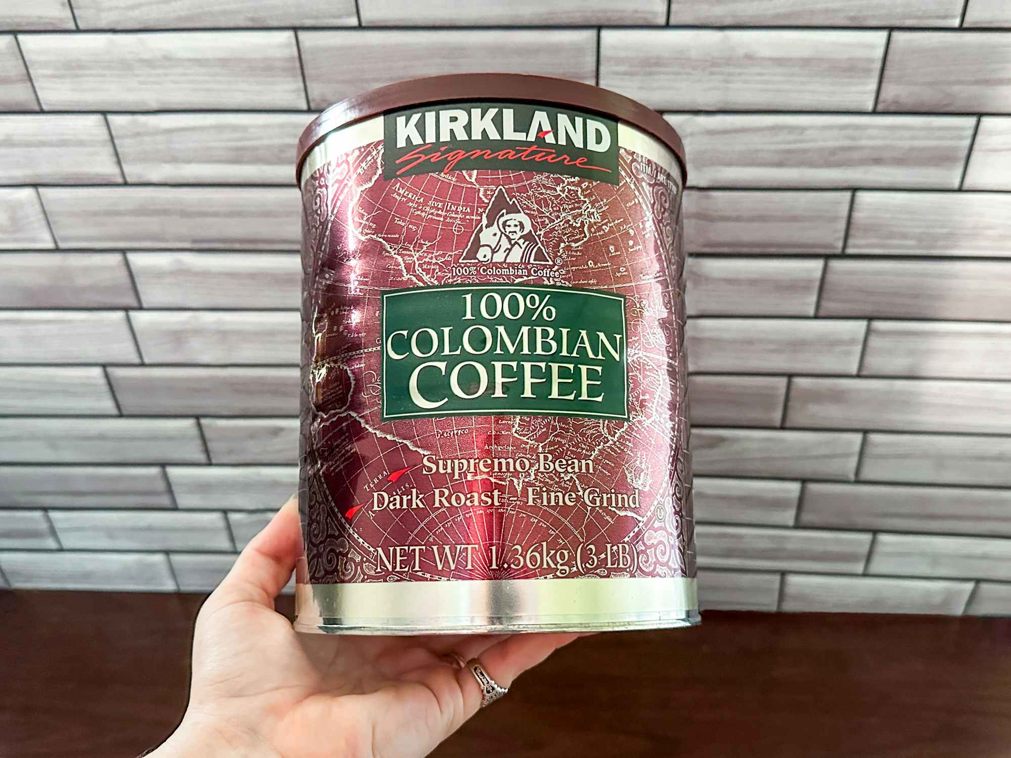 Someone holding a 3 pound can of Kirkland Columbian coffee
