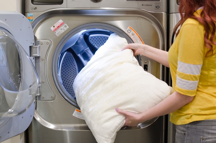 someone throwing their pillows in the washing machine. 