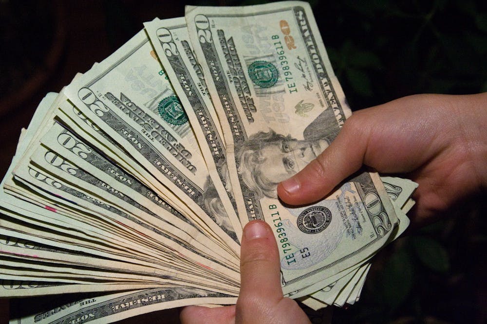 A person holding a bunch of twenty dollar bills.