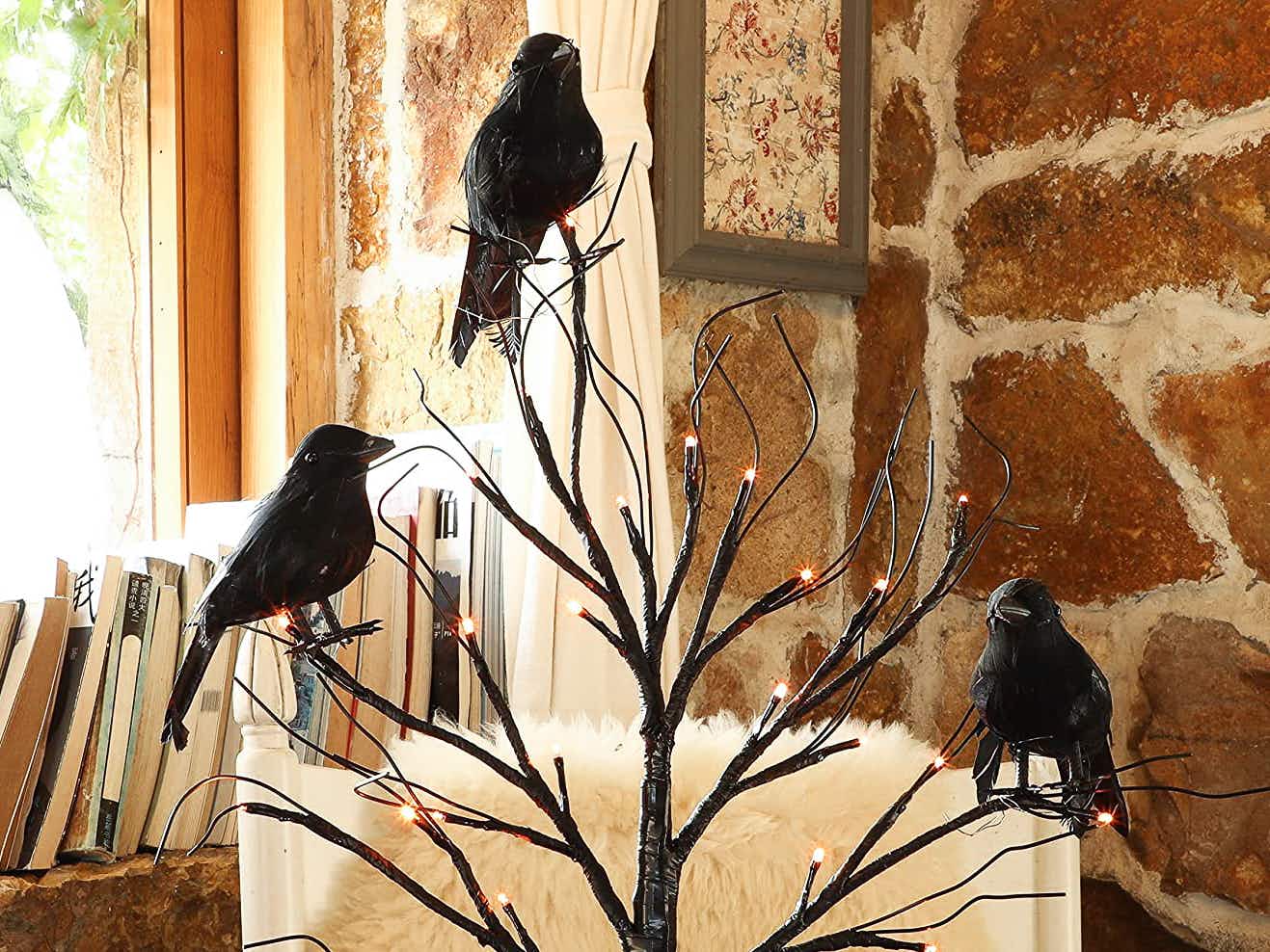 Faux crows perched on a tree decoration with LED lights in the branches.