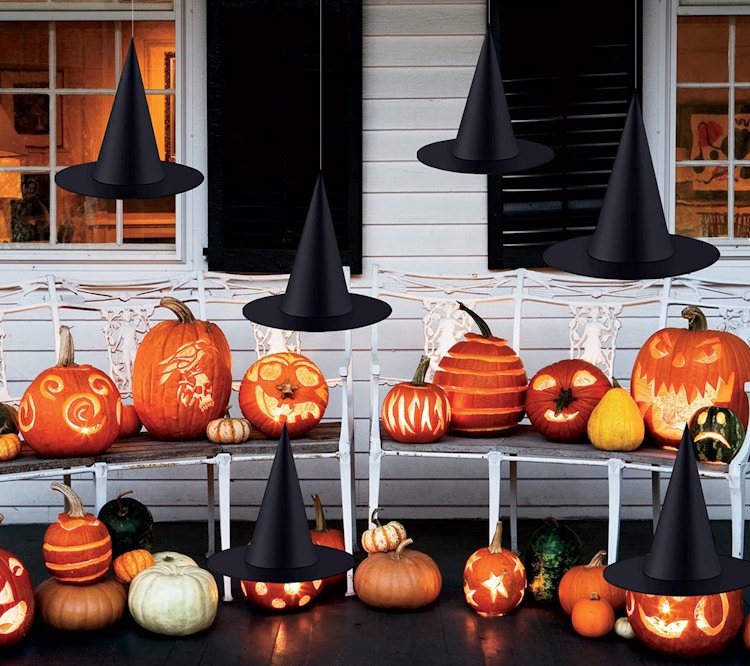 Black witch hats hanging from strings on a front porch.